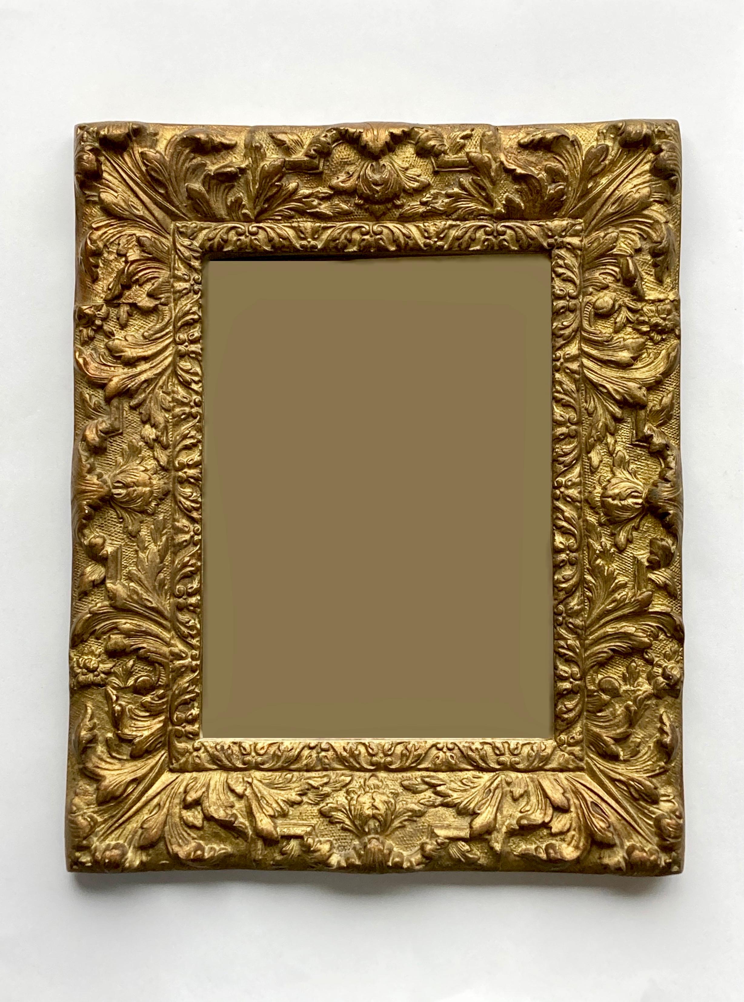 Un fabuleux miroir mural ancien provenant de France offrant un impact visuel majestueux. Le cadre est en bois massif et collé moulé et doré. Il est décoré de feuilles et de fleurs voluptueuses de style Louis XVI. Le cadre a probablement reçu