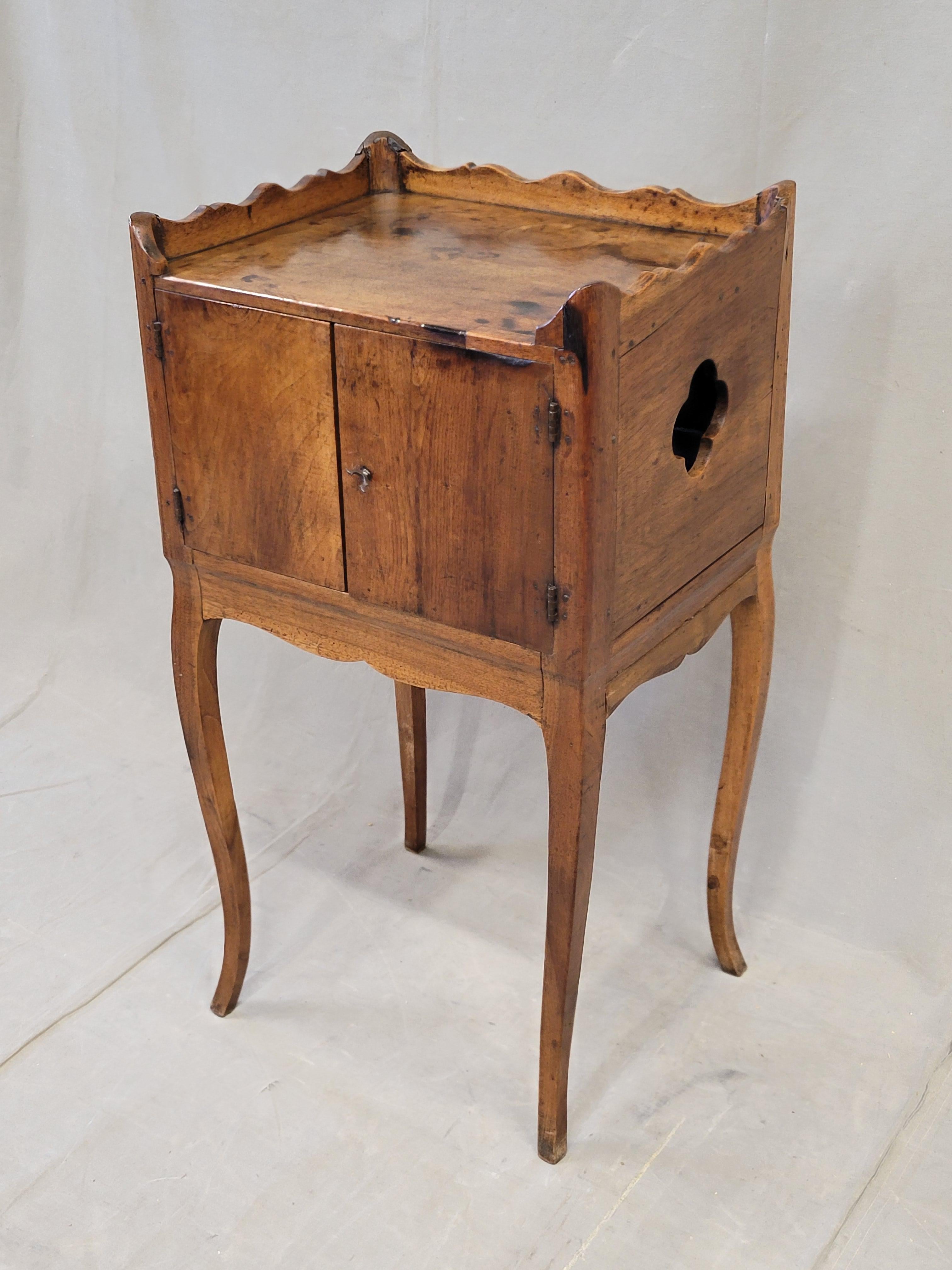 An elegantly crafted antique mid to late 1800s French Louis XV style walnut and cherry small side table or nightstand (table de chevet). The doors open to reveal storage inside and there is a 