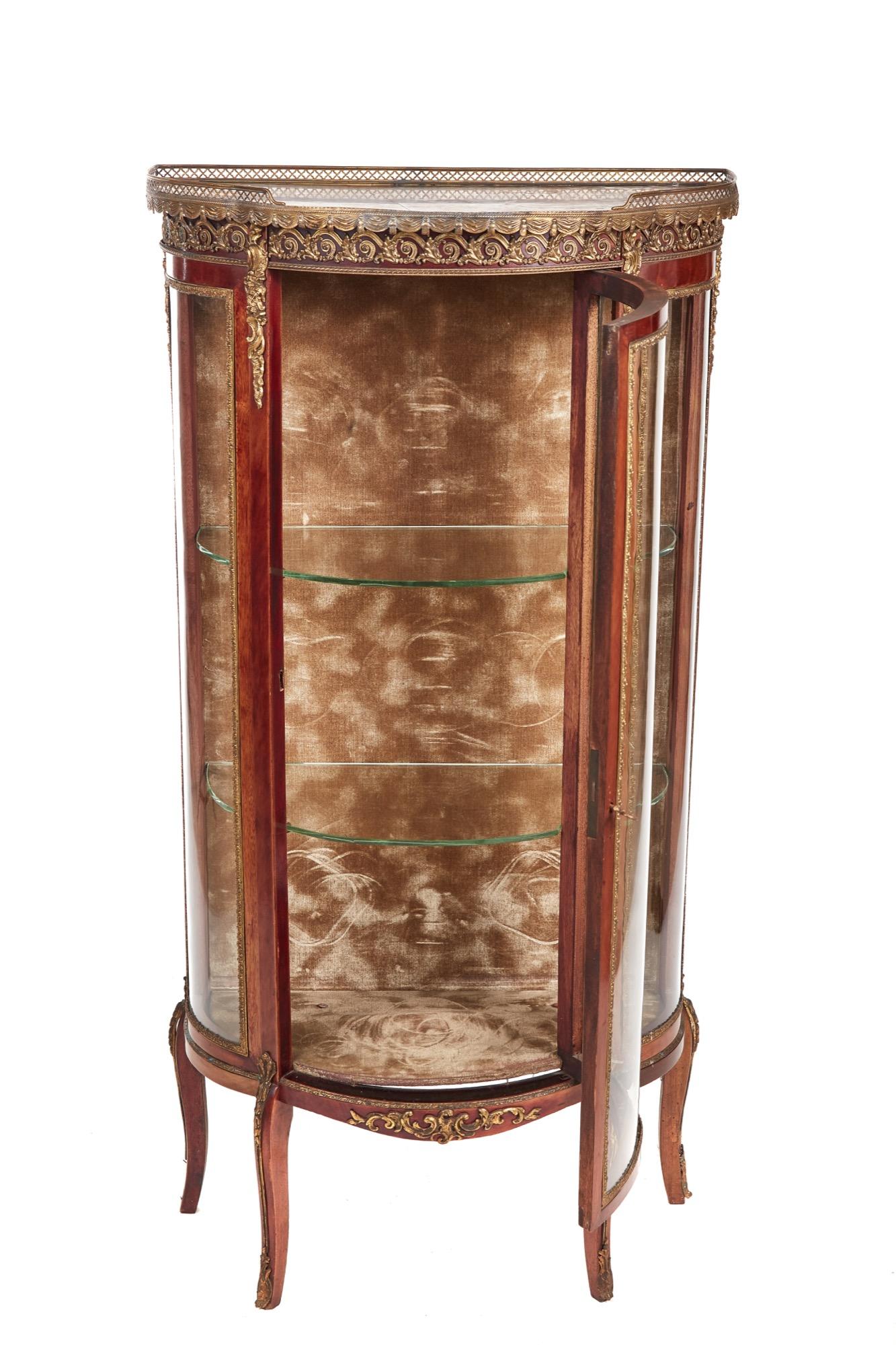 Antique 19th century French mahogany and gilded brass vitrine which has a beautiful pierced brass gilded gallery and inset marble. The bowed glazed shaped ends has very attractive gilded mounts and the bow fronted doors open to reveal the original