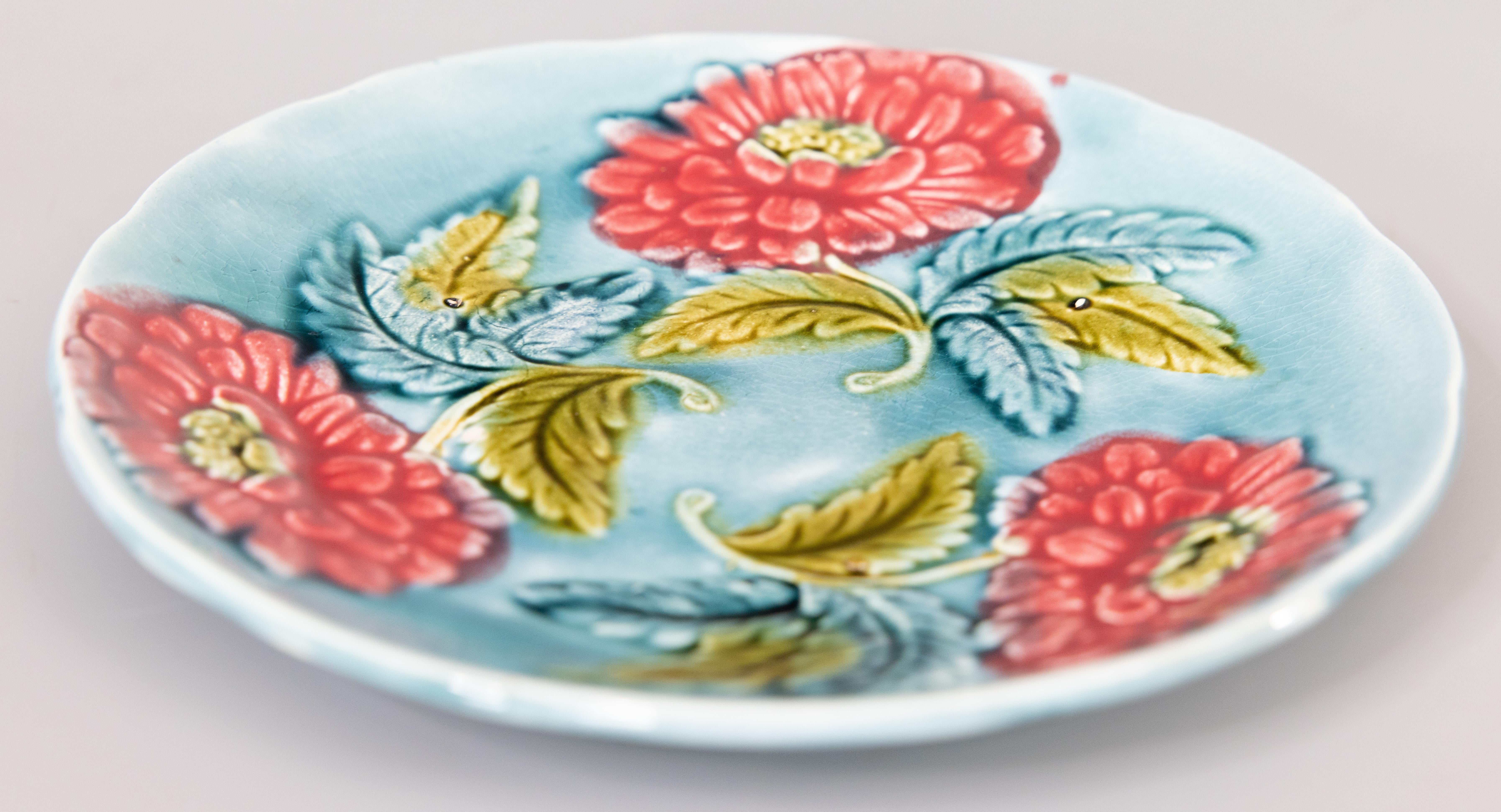 A lovely antique French majolica floral plate, circa 1890. This beautiful French country style plate has hand painted pink flowers and leaves on a light aqua blue background. It would be wonderful added to a collection or displayed on a wall or