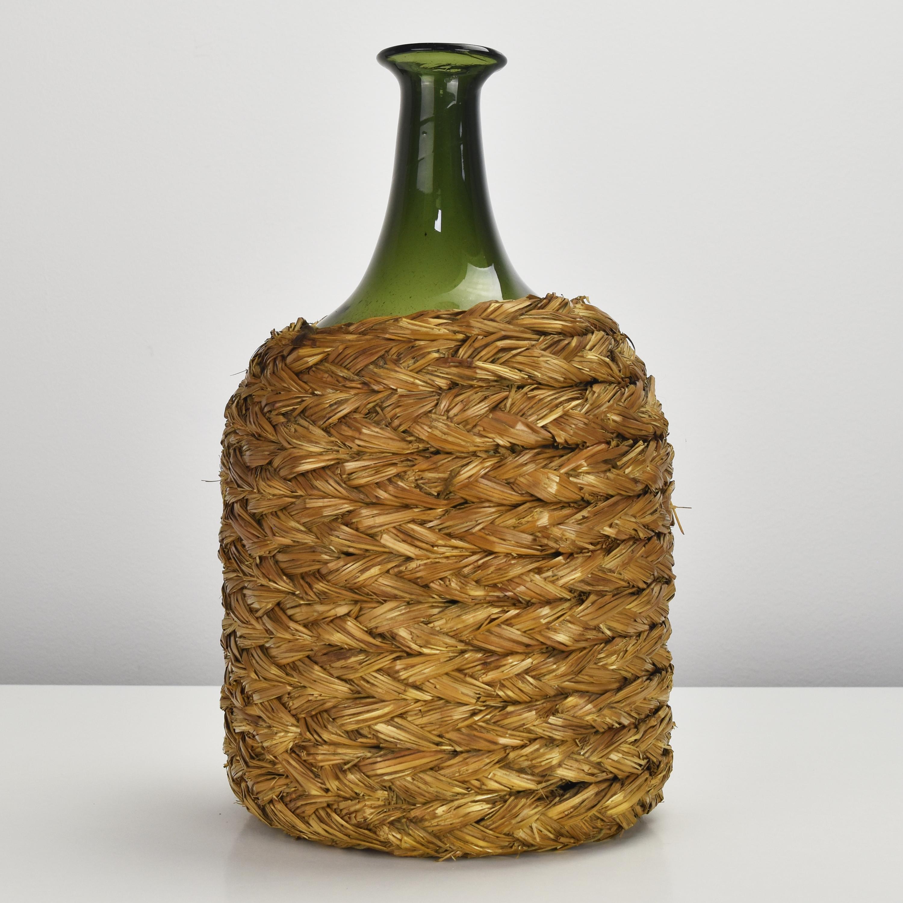 This antique demijohn is a beautifully crafted, handmade and mouthblown green glass wine bottle that is housed in a rustic straw basket. 

Dating back to the second half of the 19th century, this piece is a true antique and a rare find. The