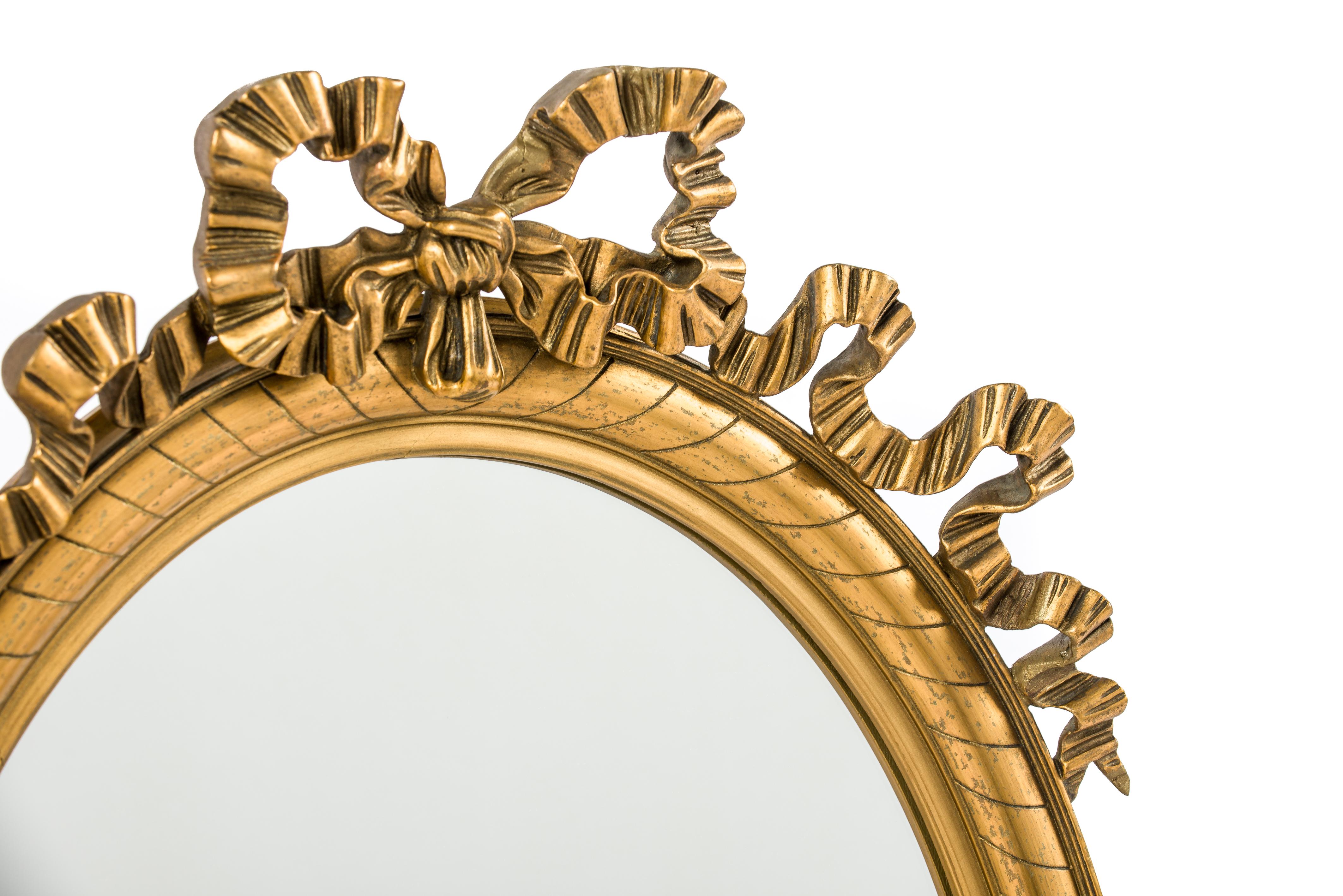 This beautiful antique oval mirror was made in Northern France in the late 19th century, circa 1890. 
It has a solid limewood base smoothened with gesso and decorated with typical Louis Seize ornaments such as the laurel garlands running across the