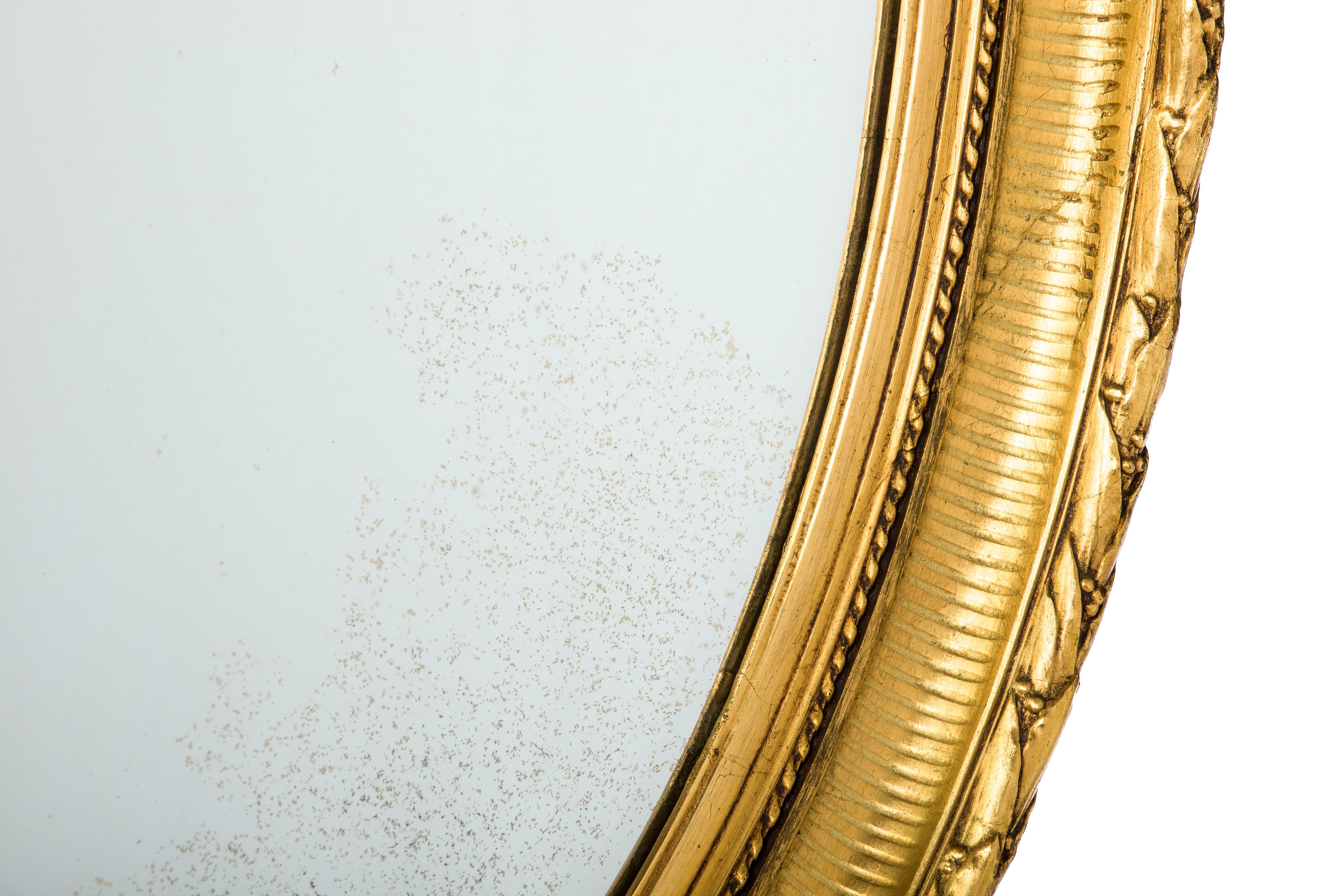 Dieser schöne, große, ovale, blattvergoldete Spiegel wurde im späten 19. Jahrhundert, um 1890, in Nordfrankreich hergestellt. Der Spiegel hat einen Rahmen aus massivem Lindenholz, der geglättet und mit Gipsabdrücken verziert ist. 
Der am höchsten