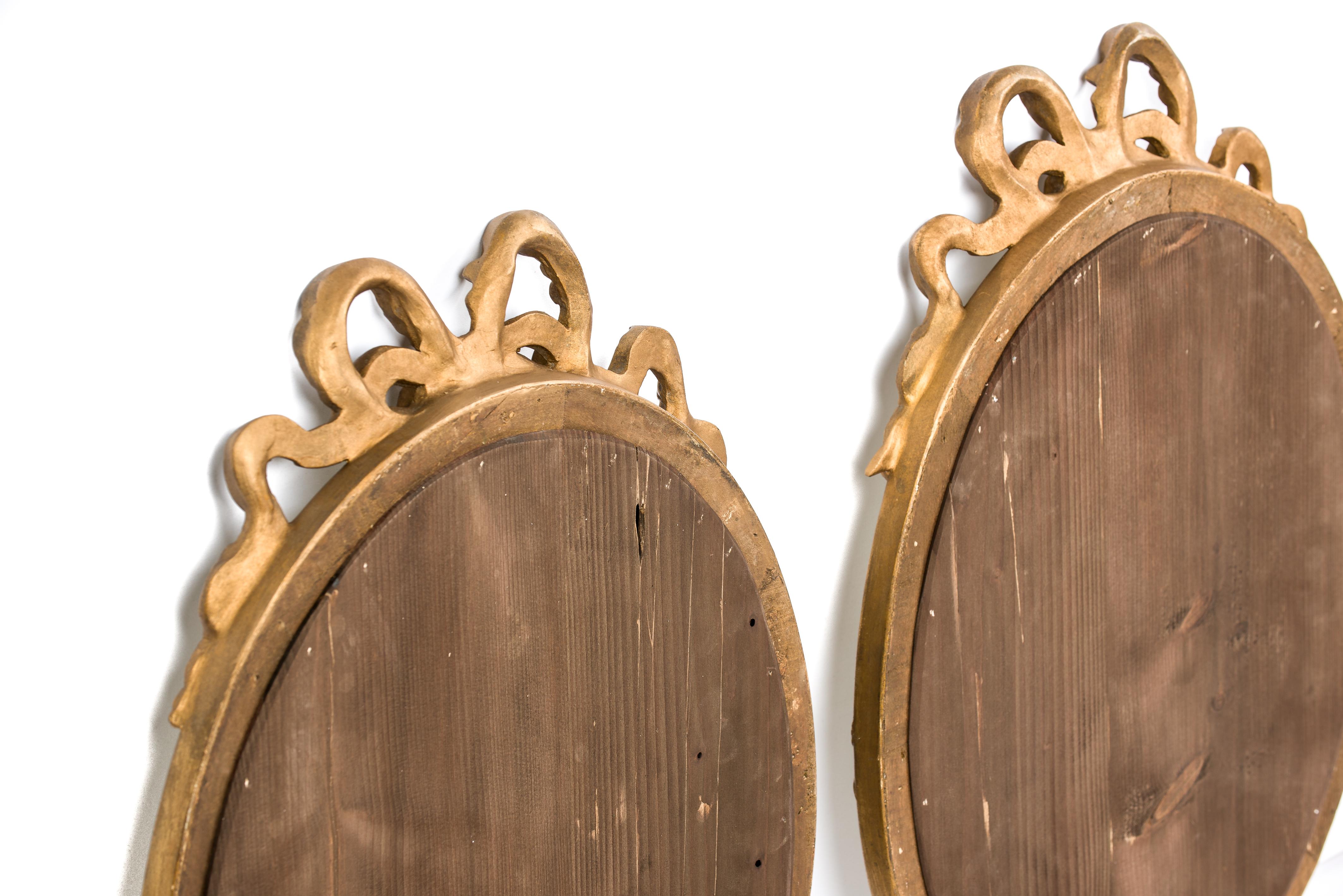 Paire de miroirs ovales français anciens du 19ème siècle en or doré avec ruban en forme de nœud papillon Bon état - En vente à Casteren, NL