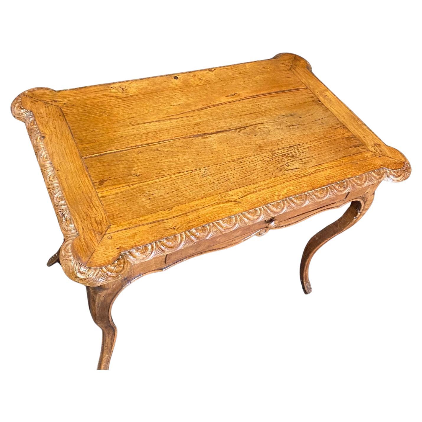Ancienne table d'appoint ou bureau en noyer de style provincial Louis XV du 19e siècle, avec un plateau rectangulaire incurvé en surplomb avec un centre inséré, des bords sculptés et une frise serpentine avec un tiroir central.  Pieds cabriole