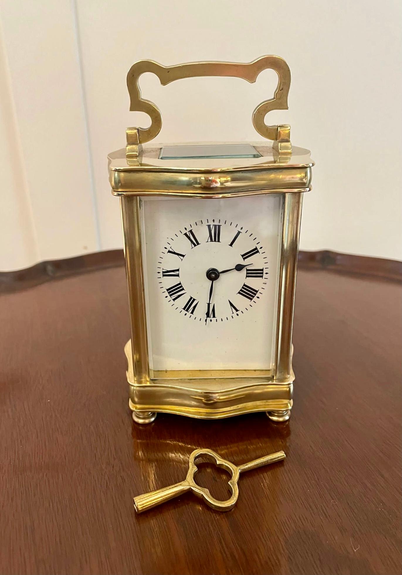 Antique French quality brass carriage clock having a quality brass serpentine shaped case with bevelled glass panels and door, shaped carrying handle to the top, enamel dial with original hands and Roman numerals, eight day movement and original