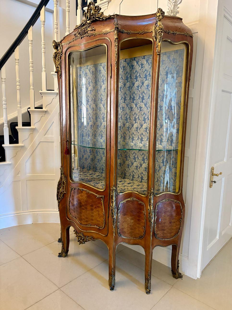 Vitrine ancienne du 19ème siècle en bois de roi et bronze doré, de forme serpentine, avec incrustation de bois de roi et de parquet et montures en bronze doré de qualité.  une porte simple au centre s'ouvrant pour révéler deux étagères de