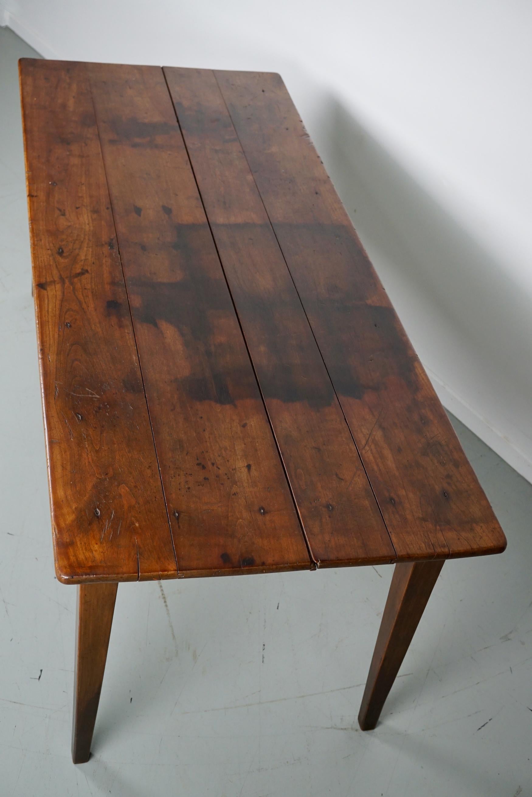 This elegant table was made in France in the 19th century. The table was made in fruitwood with beautiful grain patterns. It has a very warm light color and the table shows many marks of use, old repairs and a has a great patina. The knee height is