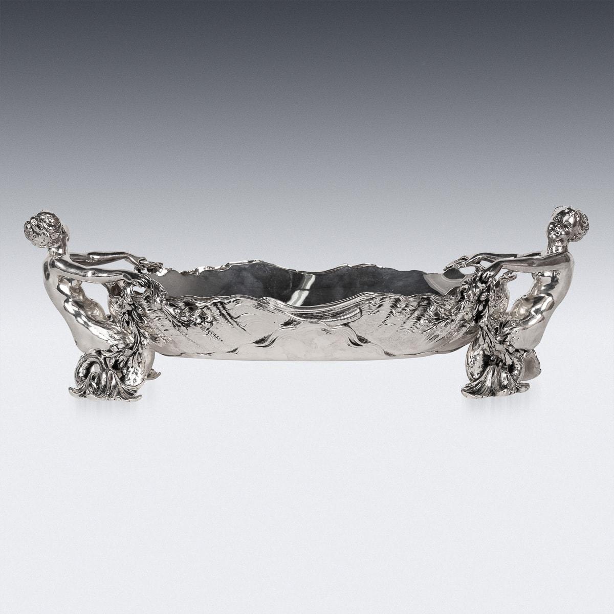 Antique 19th Century French grandiose silver-plated figural Jardinière takes center stage, accompanied by a pair of finely crafted mermen supporting an elongated dish in rococo style, complete with a removable liner. Hallmarked Christofle, numbered