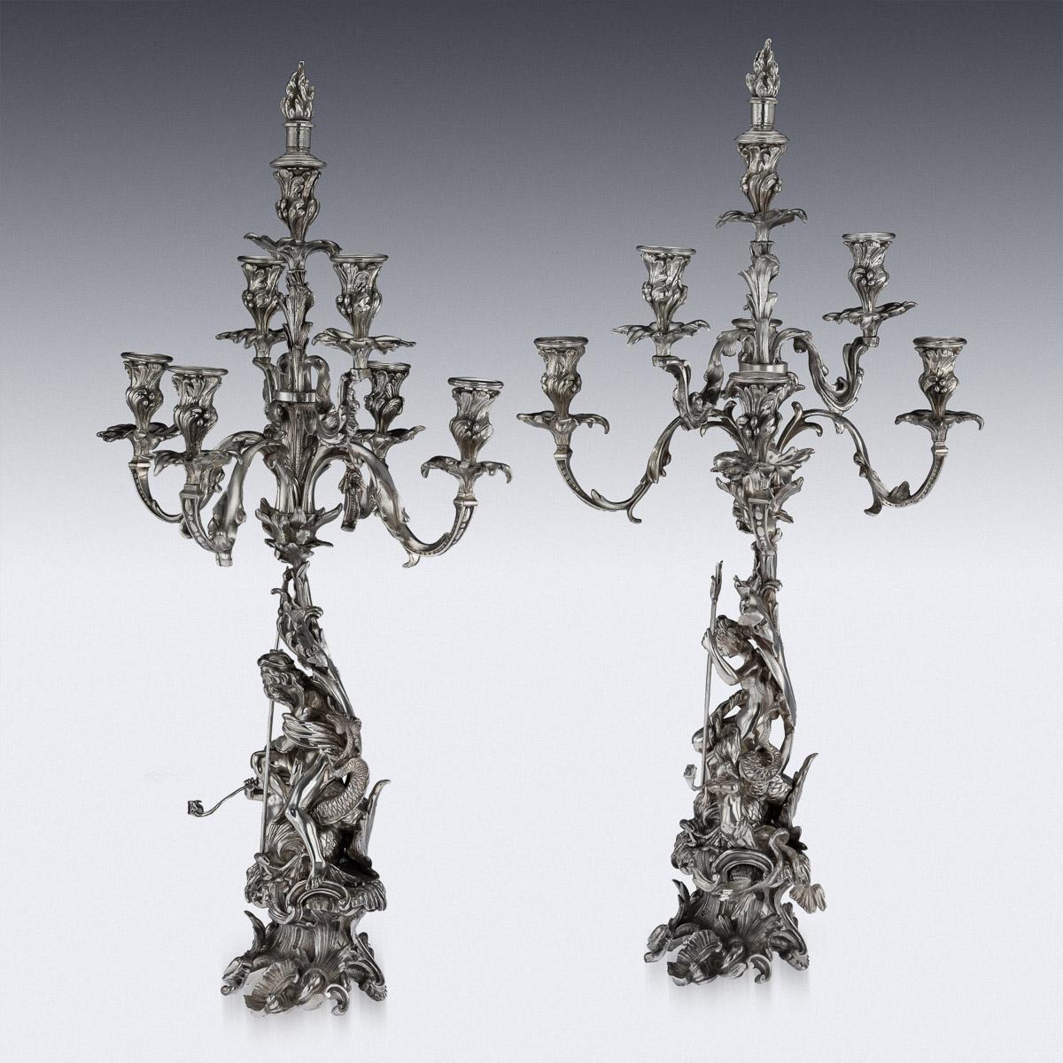 Antique 19th century French silvered bronze pair of monumental sculptural candelabra on rococo bases, representing Poseidon and Amphitrite, each holding a trident and resting on a coiled mythical dolphin, bases supporting an acanthus leaf