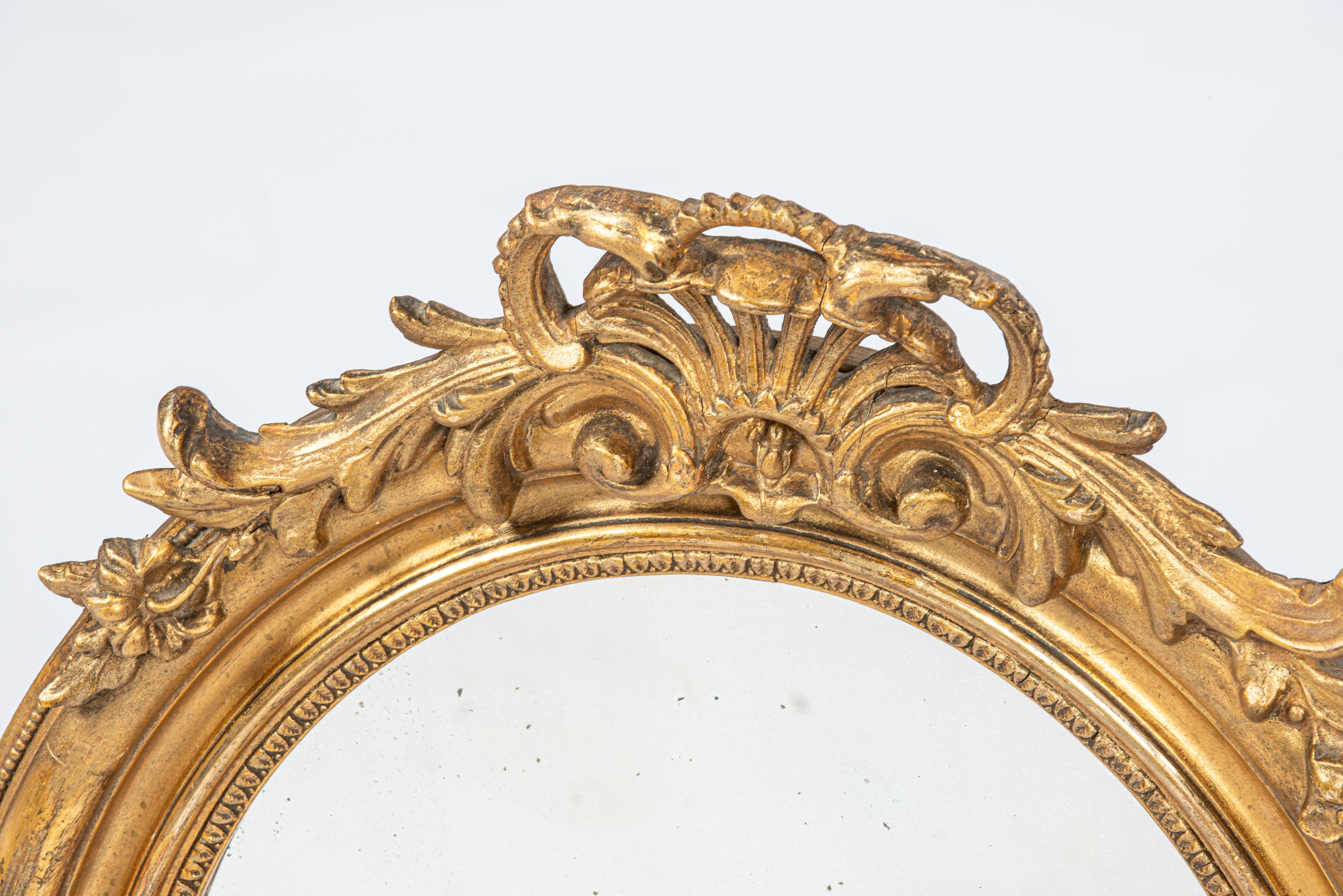 On offer here is a beautiful small oval mirror, crafted in France in the latter half of the 19th century, circa 1870. The mirror frame features a smooth pine wood frame coated with gesso. It's adorned with rich ornamentation including shell motifs,