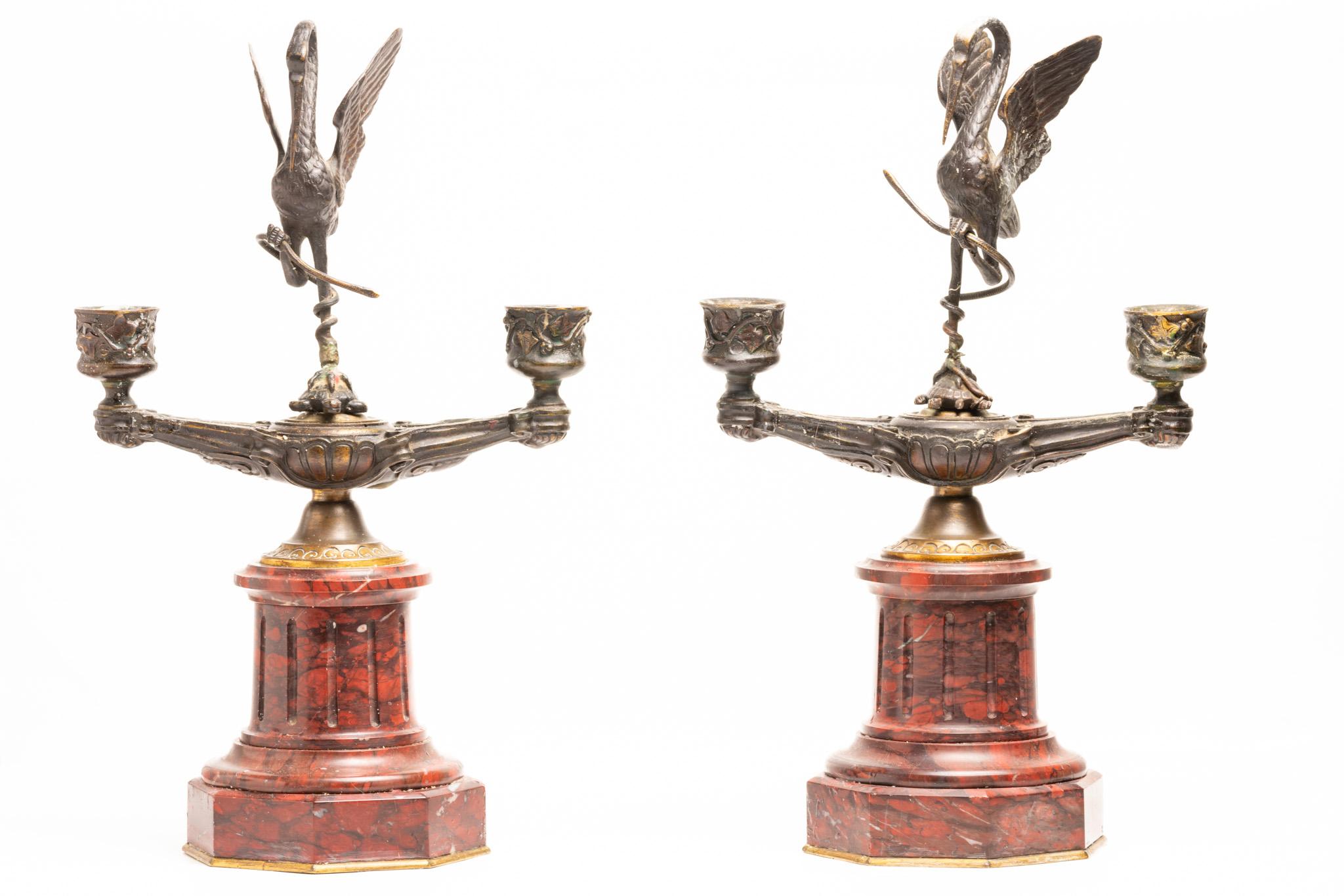 Cette paire de chandeliers anciens en bronze et marbre rouge du XIXe siècle, avec une figure de grue debout sur le dos d'une tortue, est datée d'environ 1890, pendant le mouvement du Japonisme, et s'inspire de l'esthétique et de l'artisanat