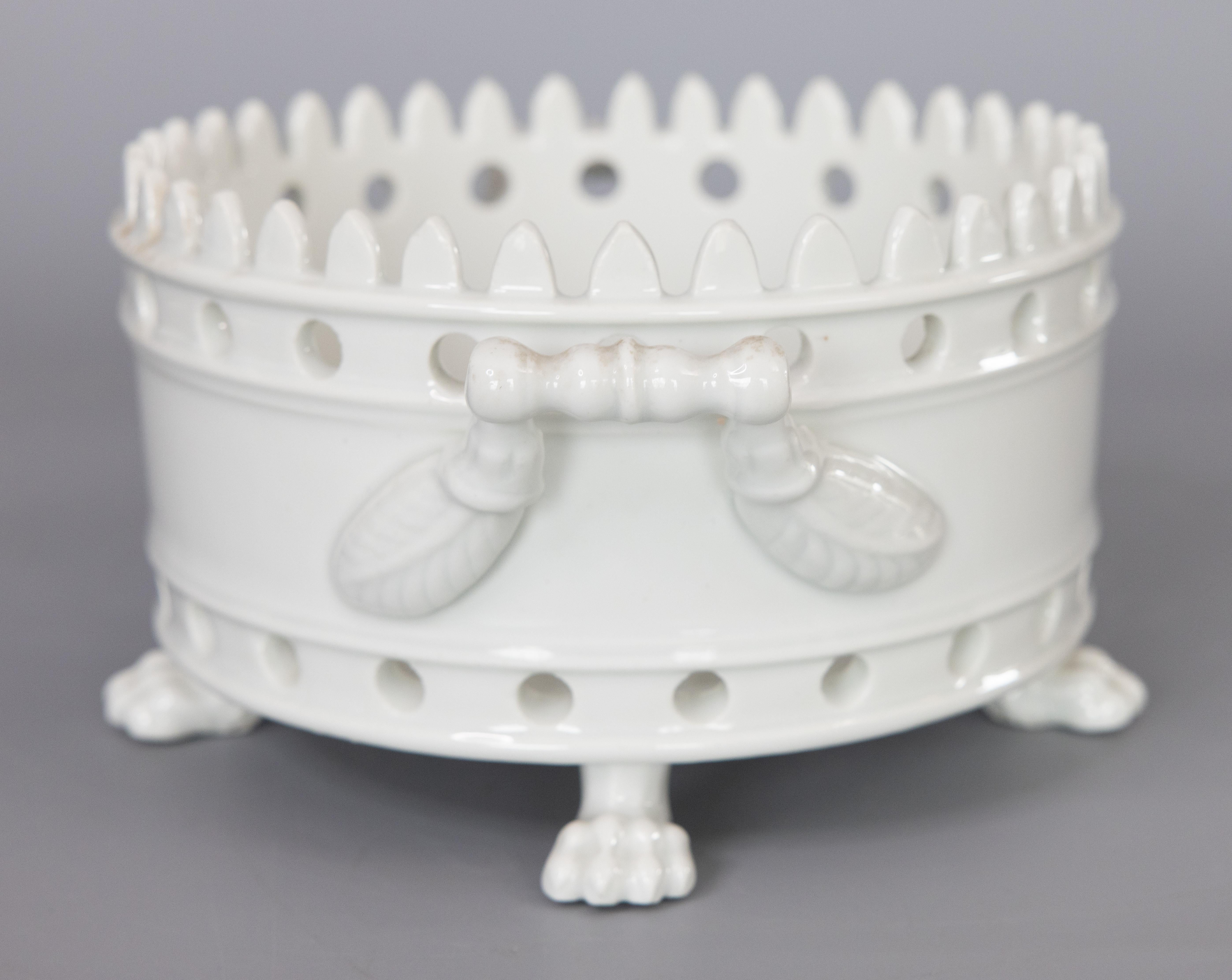 A lovely antique 19th-Century French white porcelain cachepot / jardiniere / planter. No maker's mark. This fine cachepot has a beautiful pierced design, crowned rim, scrolling leaf handles, and charming paw feet. It could be used as a planter with