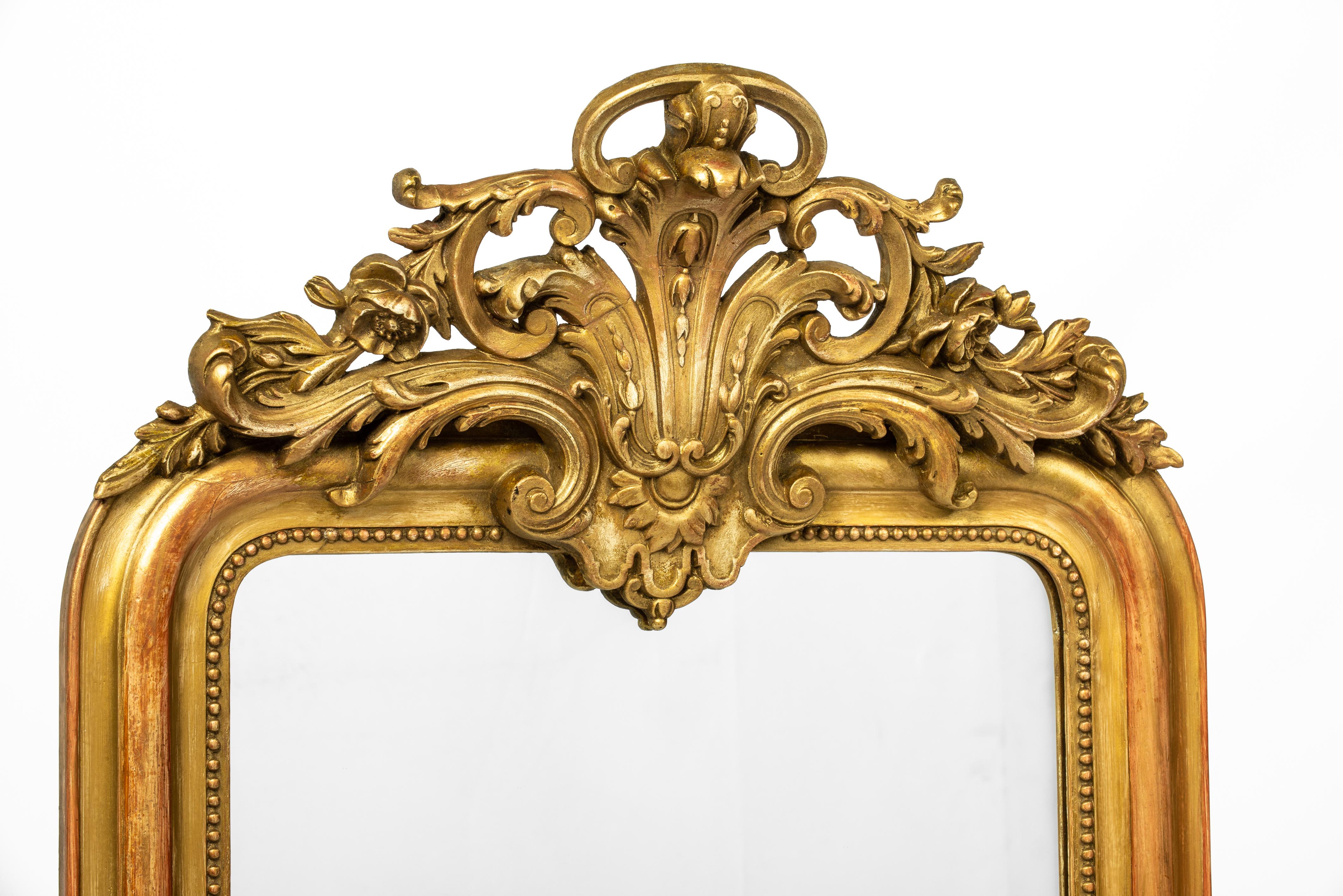 This beautiful antique mirror was made in France around 1880. It is a pure Louis Philippe mirror with its upper rounded corners and elegant frame. The most elevated part and outer mould of the frame have a red bole undercoat, while the rest of the
