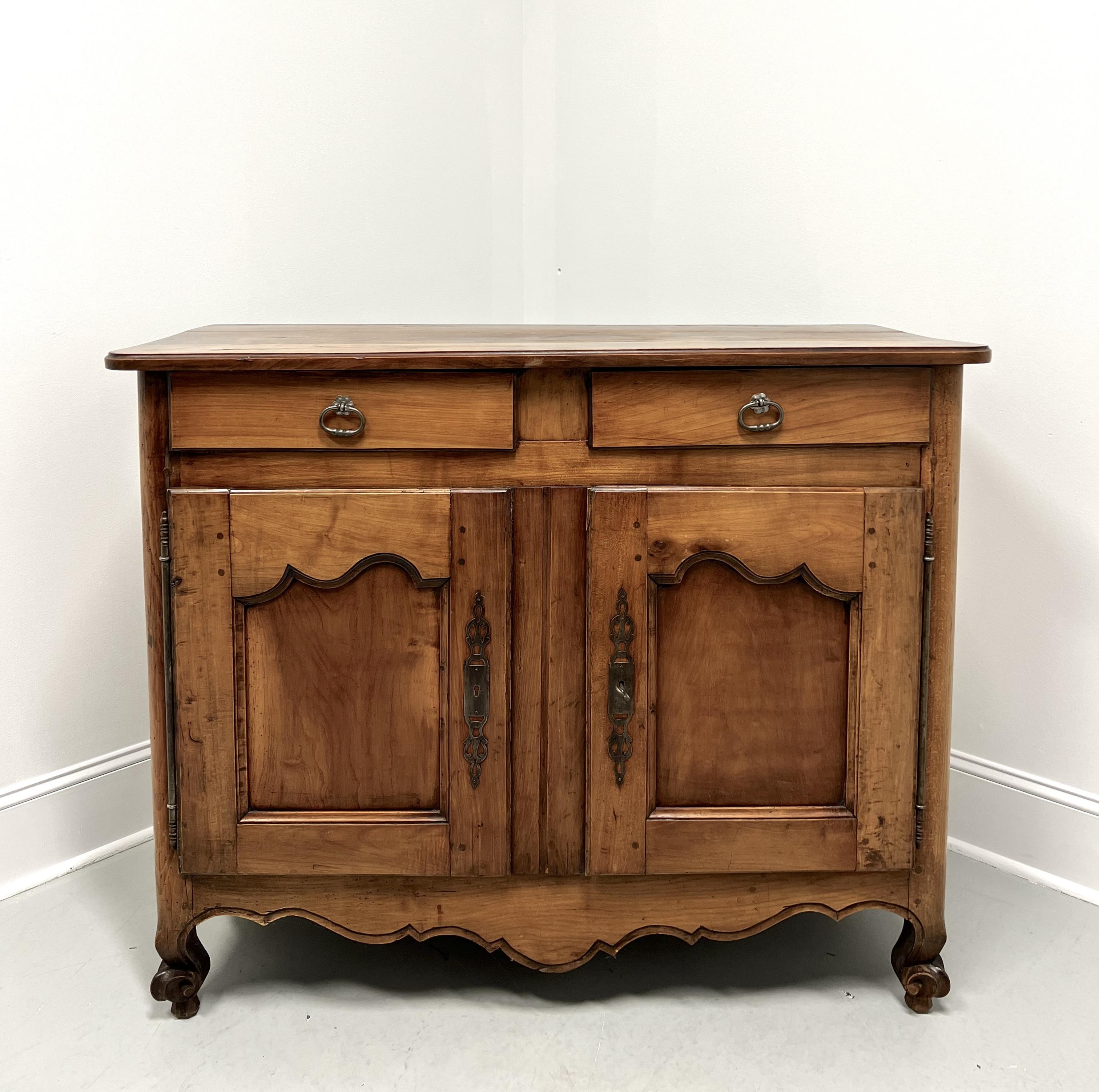 An antique French Louis XV style buffet server, unbranded. Fruitwood with brass hardware, bevel edge to the top with rounded corners, decoratively carved apron, and scroll front feet.  Features two drawers of dovetail construction, over two lockable