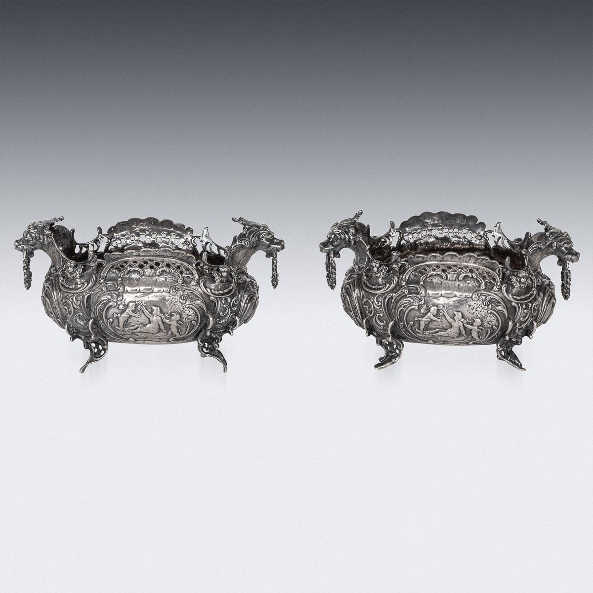 Antique late-19th Century German pair of solid silver bowls, each exceptionally decorative and ornamental on four scroll feet, the sides embossed and chased in high relief with classical scenes, depicting putti and angels, carrying flowers,