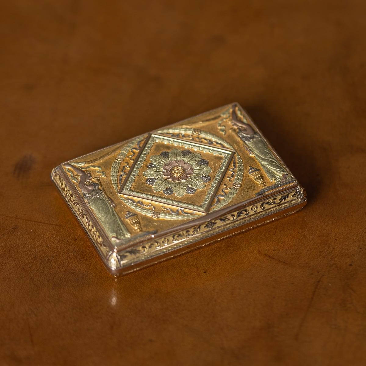 Tabatière ancienne du début du XIXe siècle en or 18 carats tricolore, de forme rectangulaire aux coins élégamment arrondis, dont le couvercle est orné d'une tête de fleur ciselée centrée dans un cadre en forme de losange, entourée d'une couronne en