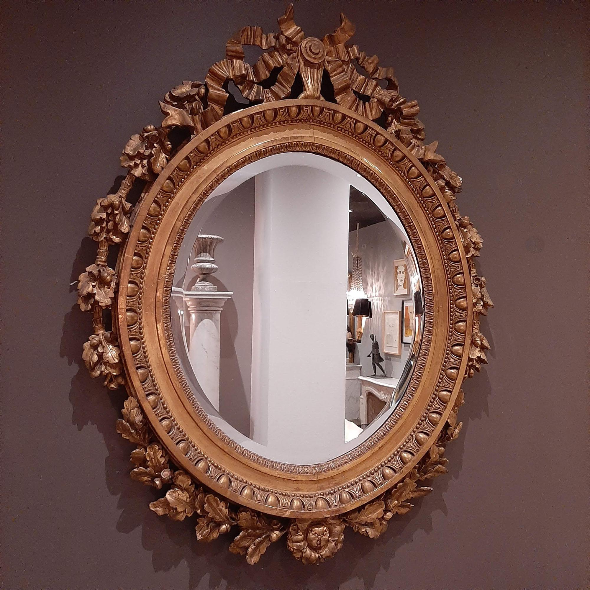 Miroir girandole ovale, doré, de style Louis XVI, datant du 19e siècle. Cadre doré magnifiquement sculpté avec un miroir à facettes.