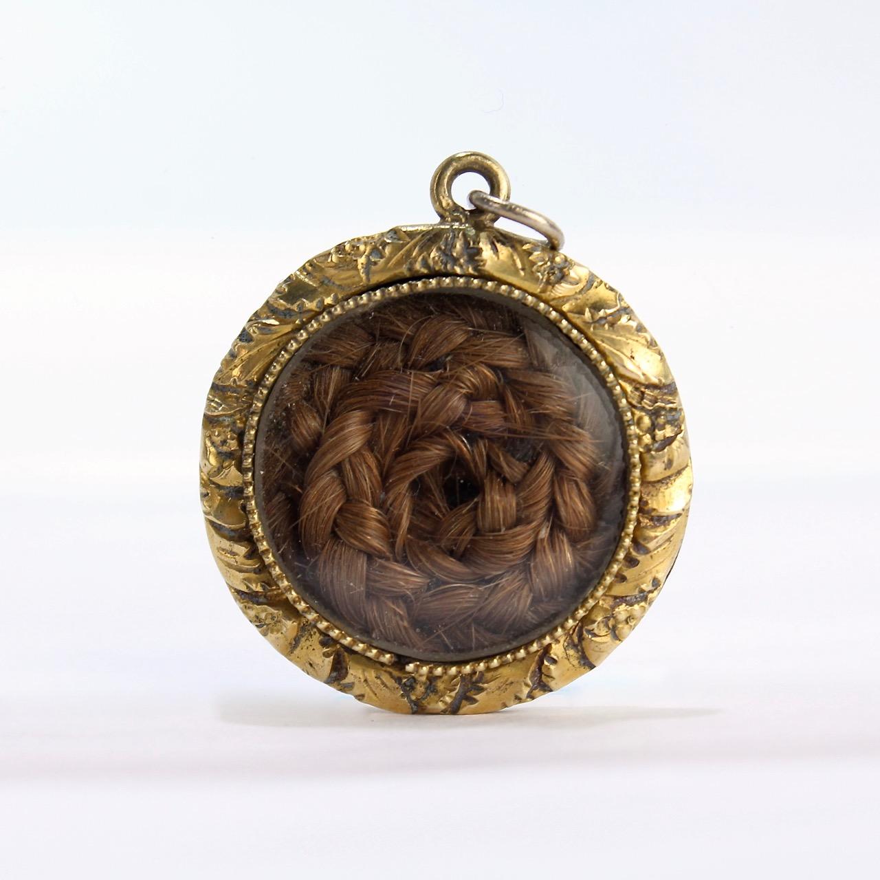 A fine late Georgian or early Victorian memorial gold-filled pendant with woven hair.

With a coil of braided hair set behind glass in a filigree-worked gold-filled pendant setting.

A rare form indeed!

In the Georgian and Victorian eras, woven