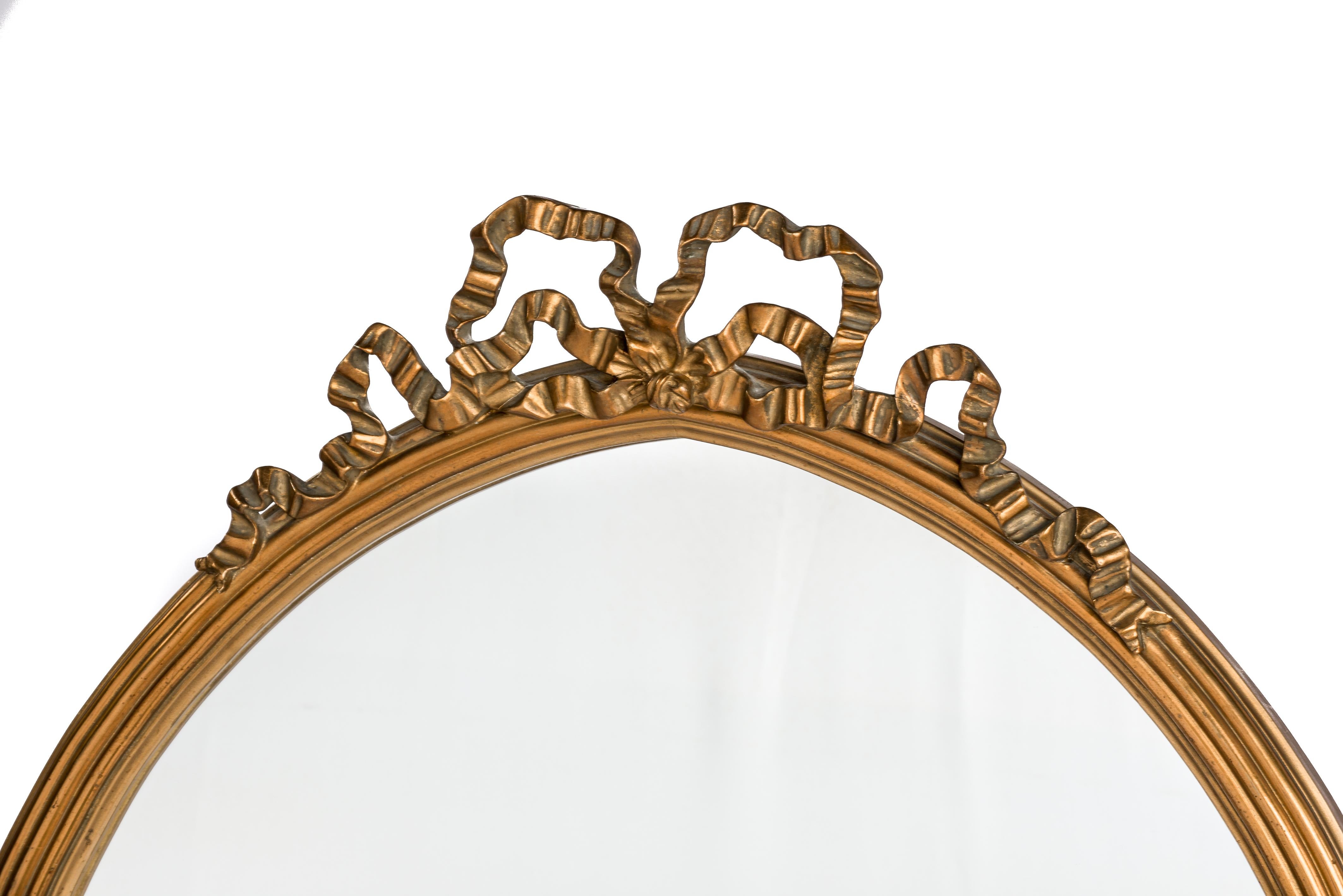 This beautiful antique mirror was made in Northern France at the end of the 19th century, circa 1890. The classic shaped Louis Seize or Empire mirror is decorated with a bow-tied ribbon over an arched top and features a ribbed frame with a solid