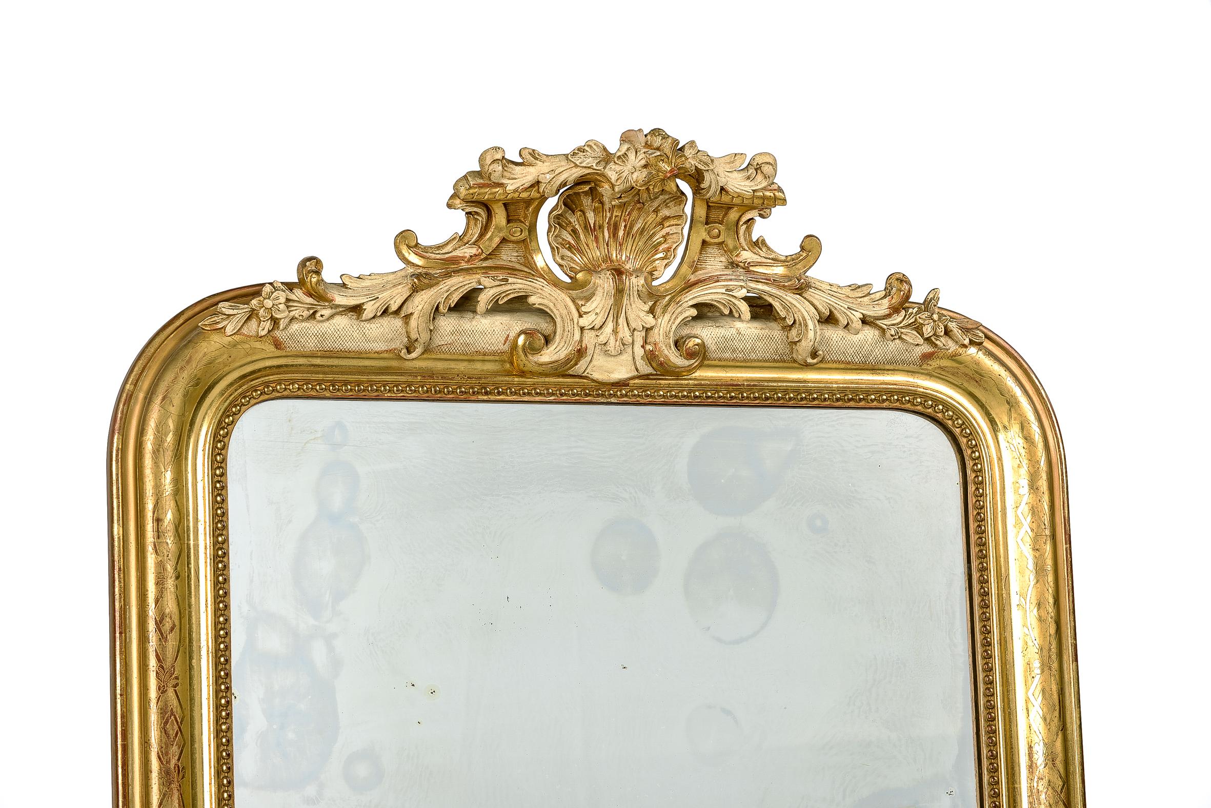A beautiful antique mirror that originates in France, circa 1870. The mirror has the upper rounded corners typical for Louis Philippe mirrors. The mirror has a rich, ornamented crest with a central scallop shell motif flanked by acanthus and