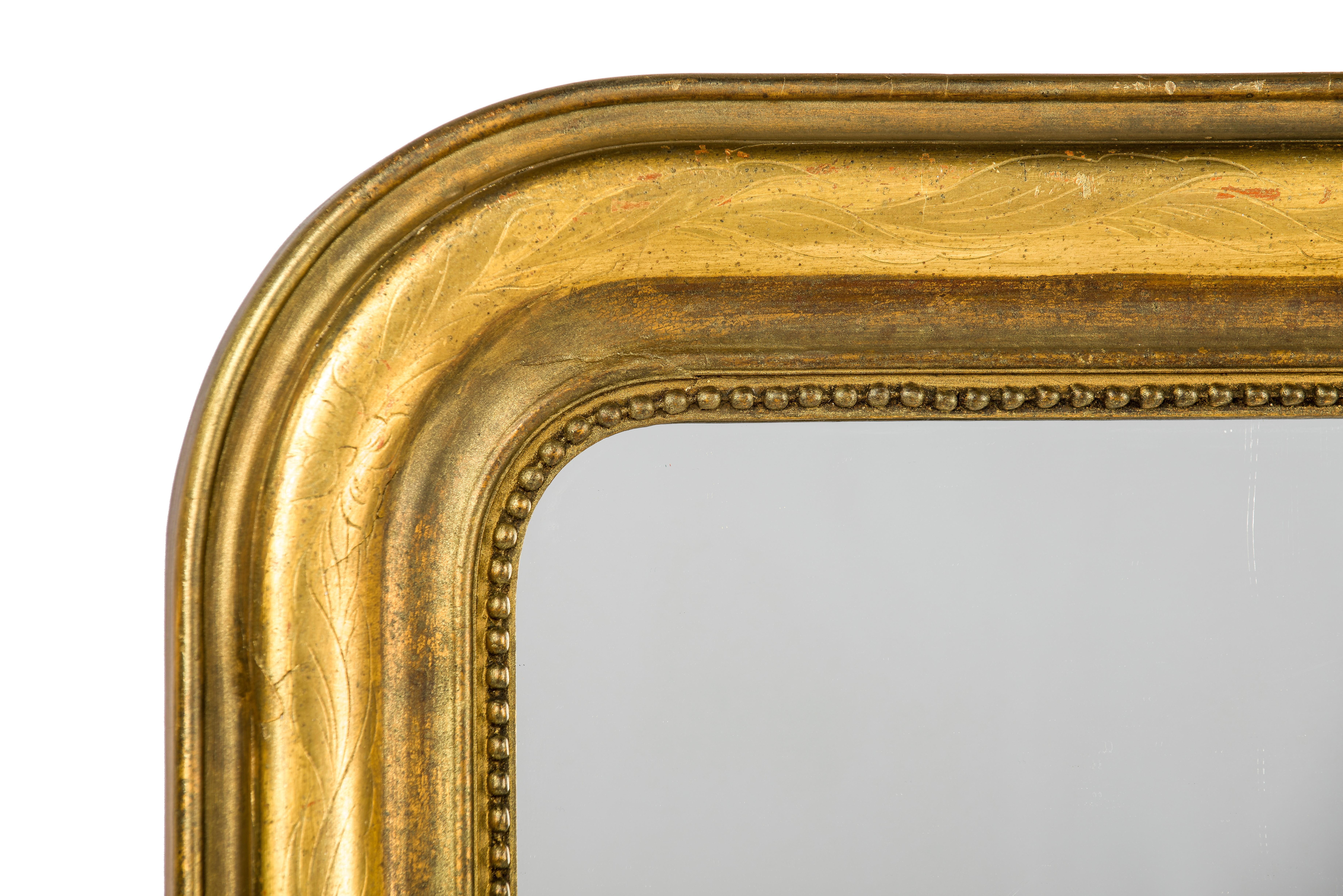 This beautiful Louis Philippe overmantel mirror was made in France, circa 1880. The mirror has a solid pine frame smoothened with gesso. The upper rounded corners are typical for the Louis Philippe style. The glass is surrounded by a classic pearl