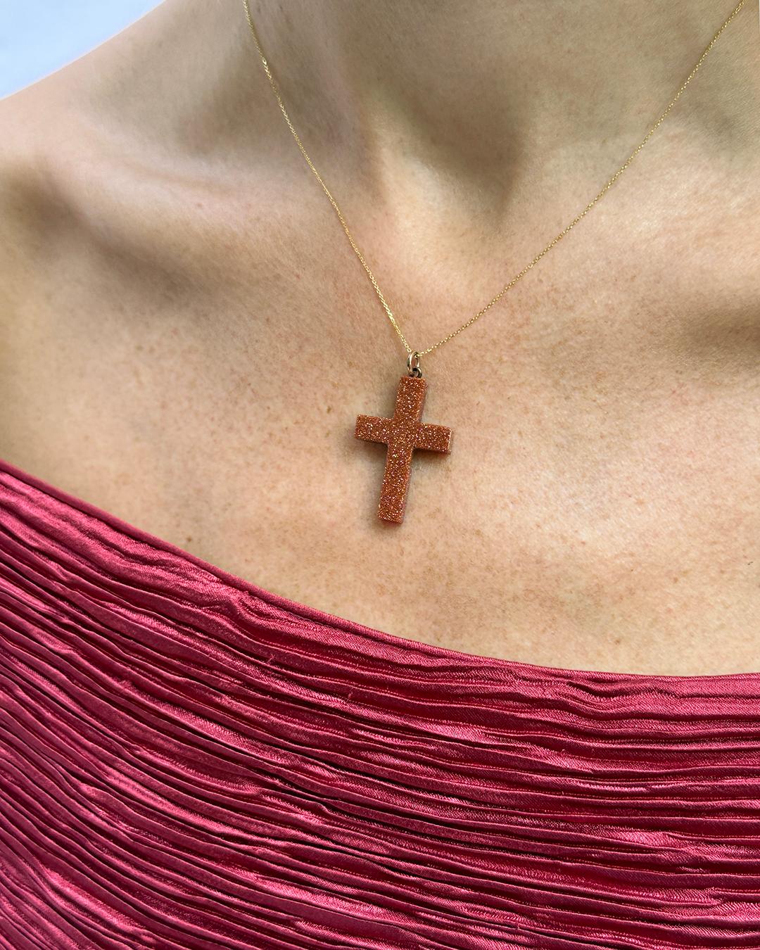 This antique goldstone cross was made in the 19th century, but it has a decidedly modern appeal. The cross's goldstone surface is a burnt orange color, with metallic flecks that sparkle with every movement. What is goldstone? Legend has it that