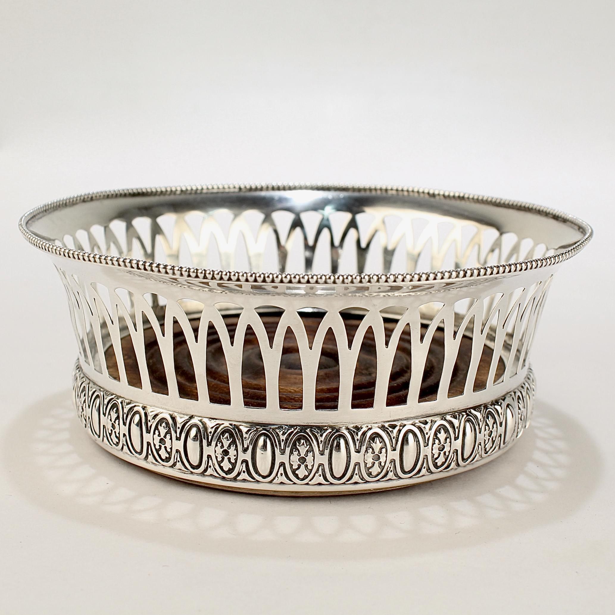 A fine antique sterling silver wine coaster.

By Gorham Silversmiths.

With a beaded rim and flared top supported by reticulated sides and an ornate base. 

Having a bird's eye maple wooden insert or base.

Simply an amazing 19th Century American