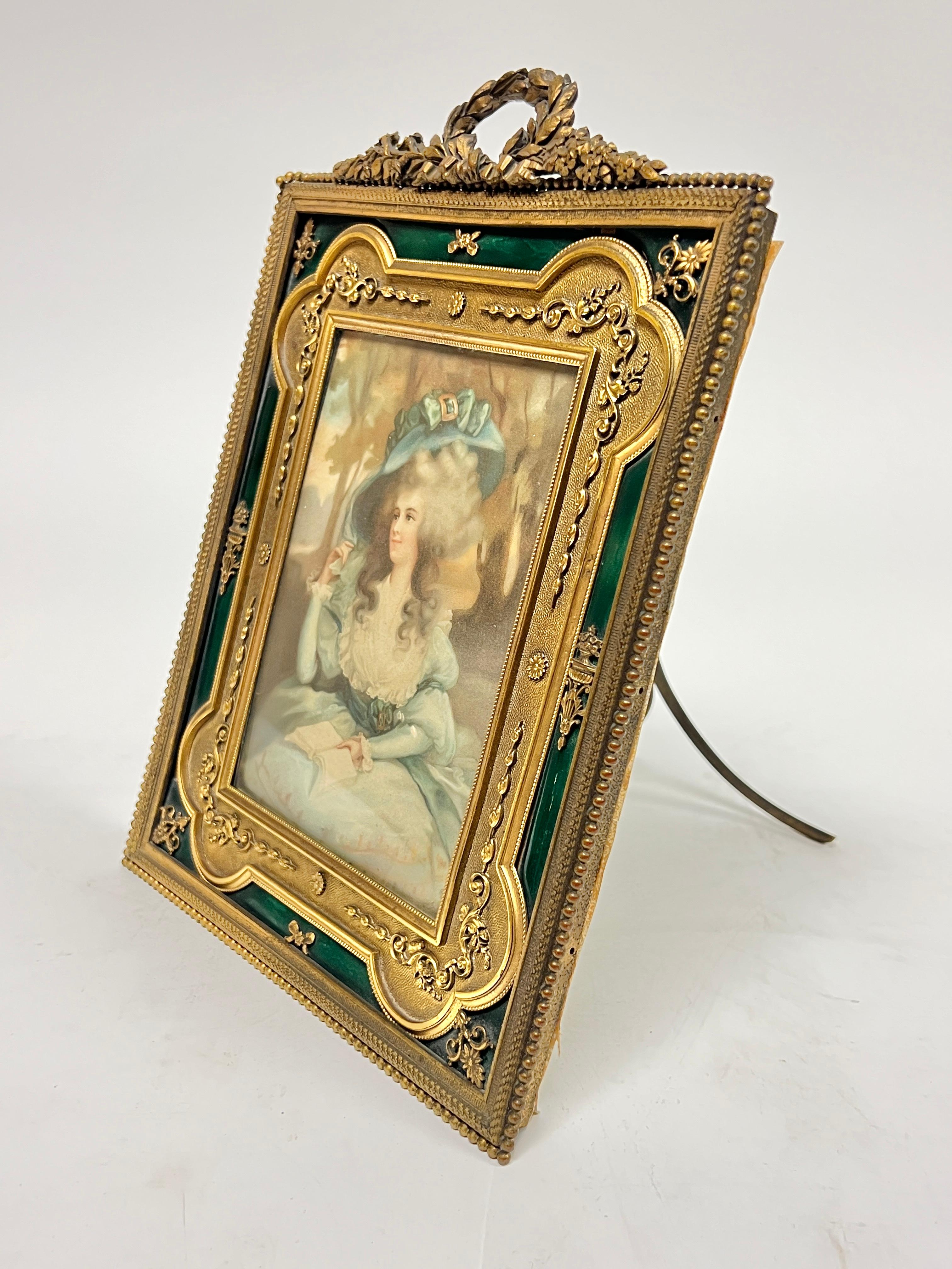 Precioso marco antiguo (siglo XIX) de bronce dorado y esmaltado con esmalte verde brillante, de 15 por 25 cm.  Puede colgarse o colocarse sobre una superficie plana.  La abertura visible mide 3 3/4 por 5 1/2 pulgadas.  Aparentemente sin firmar.  (La