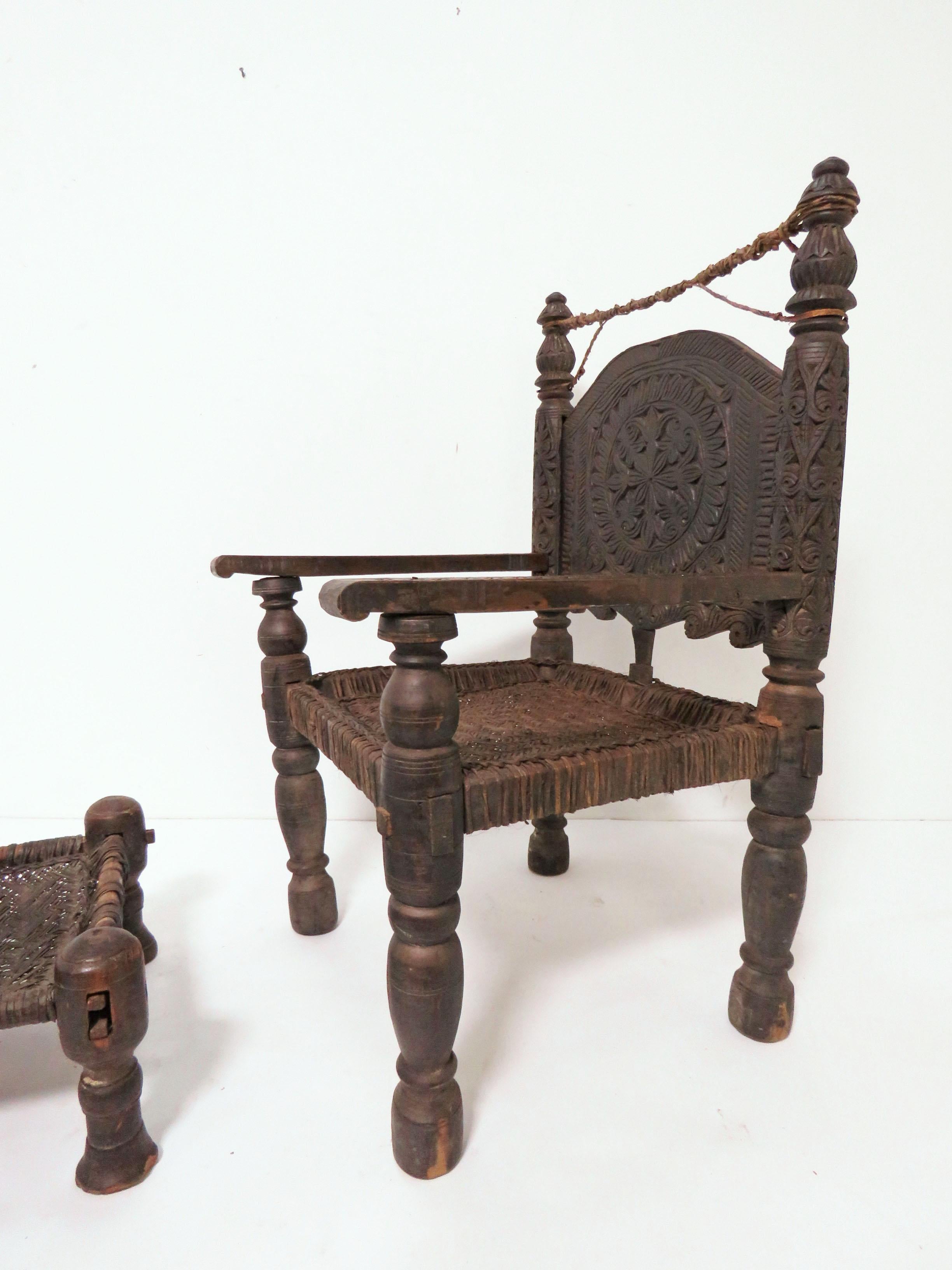 A mid to late 19th century Afghan armchair and stool, back panel ornamented with chip carving of tribal designs. Fashioned of Himalayan cedar and goat-hide and pegged together without use of nails, such chairs from the Swat Valley of the Hindu Kush