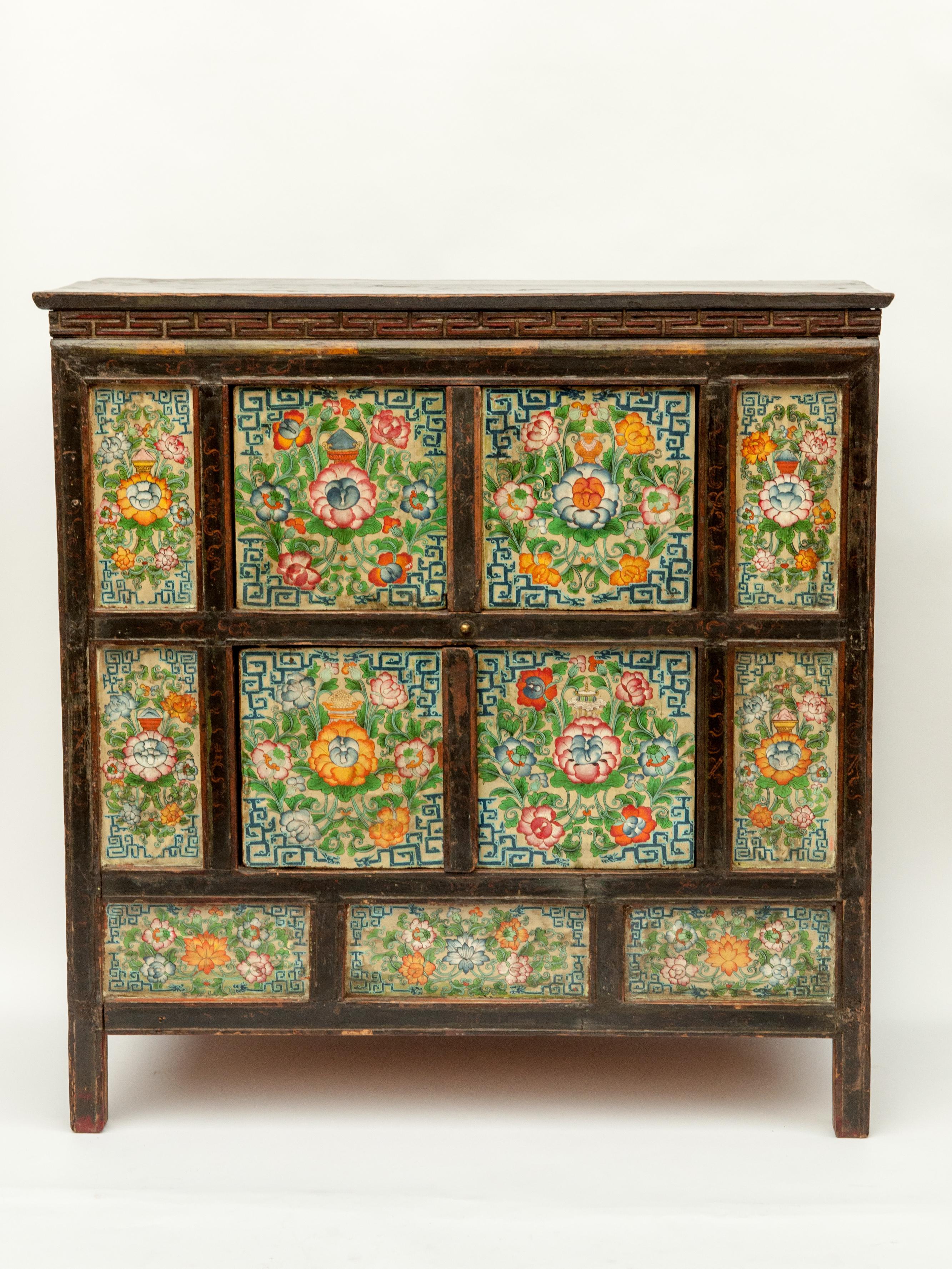 Antique 19th century hand painted Tibetan cabinet. Measures: 37 inches wide by 28 inches tall.
Floral motifs and auspicious symbols predominate in this small Tibetan cabinet, distinguished by its quality of painting, and the vibrancy of its colors.