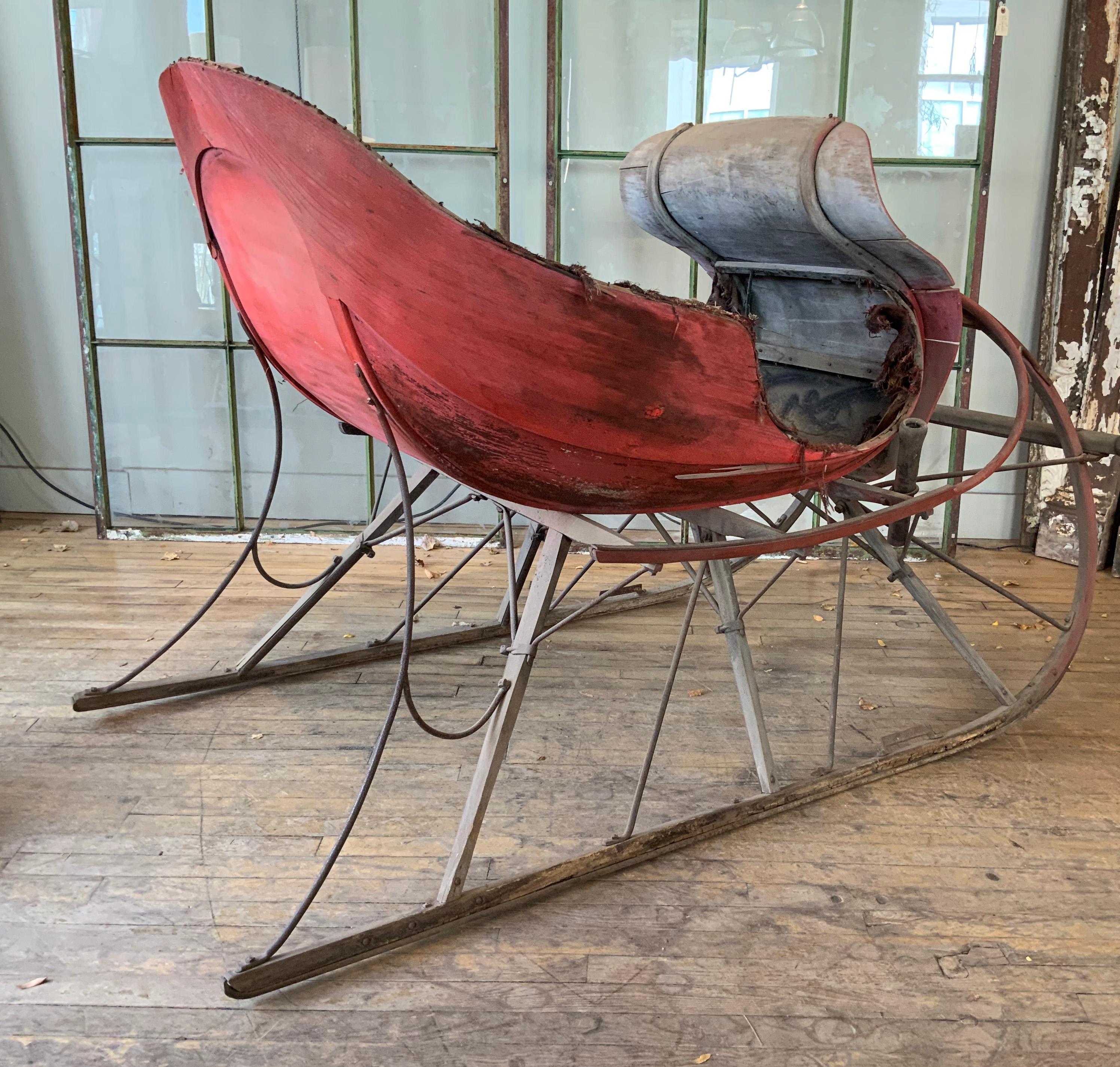 A totally charming antique late 19th century horse-drawn sleigh, in original red painted finish. beautifully sculptural, and despite some loss to the carriage as pictured, it is stable, a beautiful decorative object!
