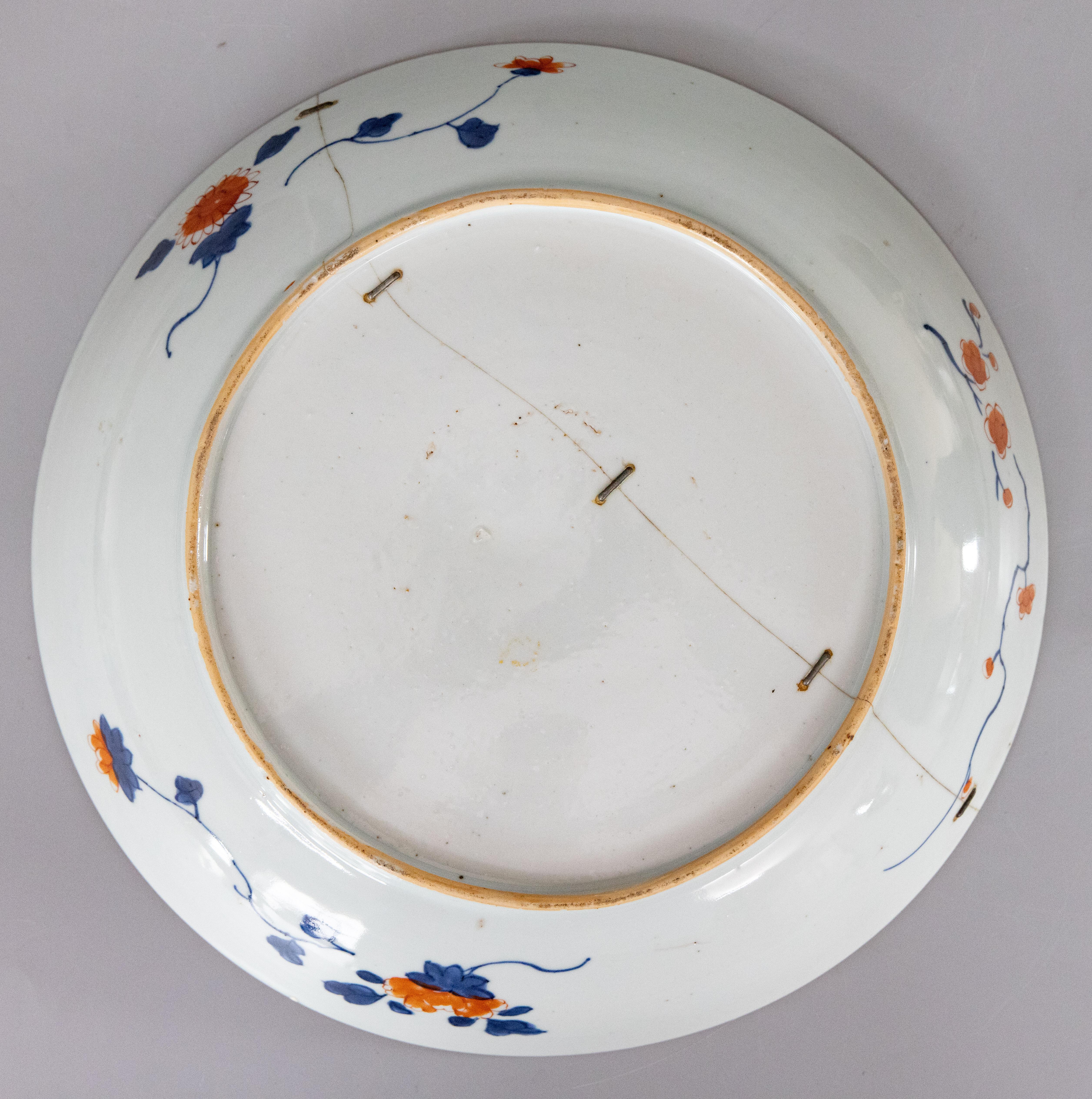 Striking 19th century antique Imari staple charger featuring vibrant oranges, blues, and golds. While a broken plate or charger would be discarded in today's era, other generations found unique ways to repair and continue using cherished treasures.