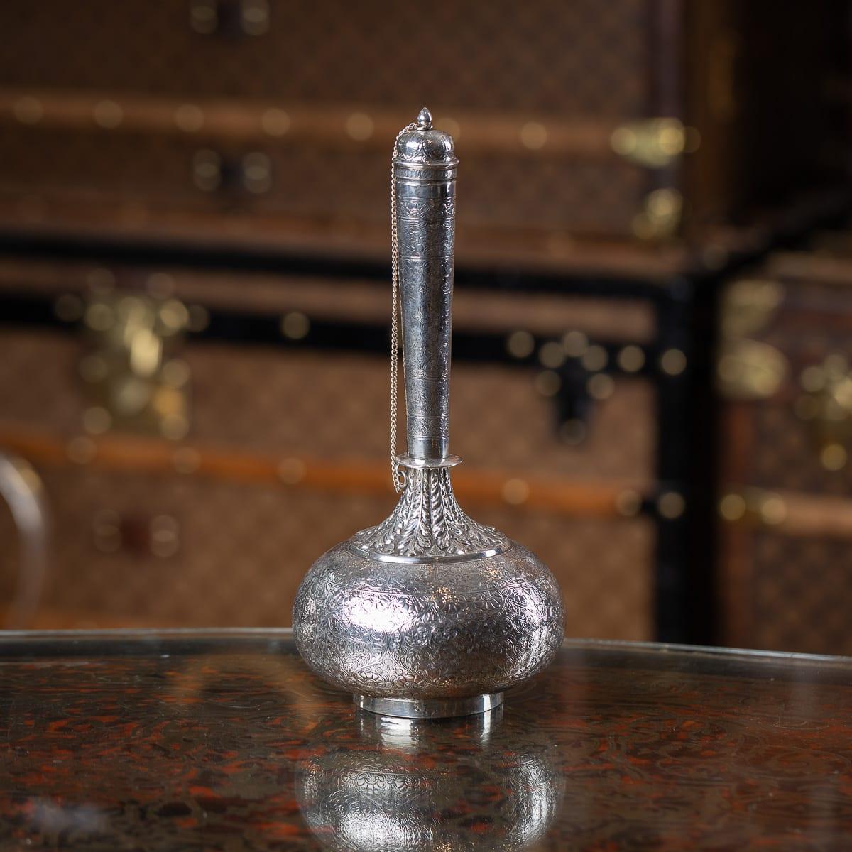 Antiguo frasco de vino o agua (surai o surahi) de plata maciza de la India (Lucknow) del siglo XIX, con cuerpo globular, cuello cilíndrico alto y ahusado, tapa abombada con bisagra y remate en forma de capullo. Inusualmente, la pieza está ricamente