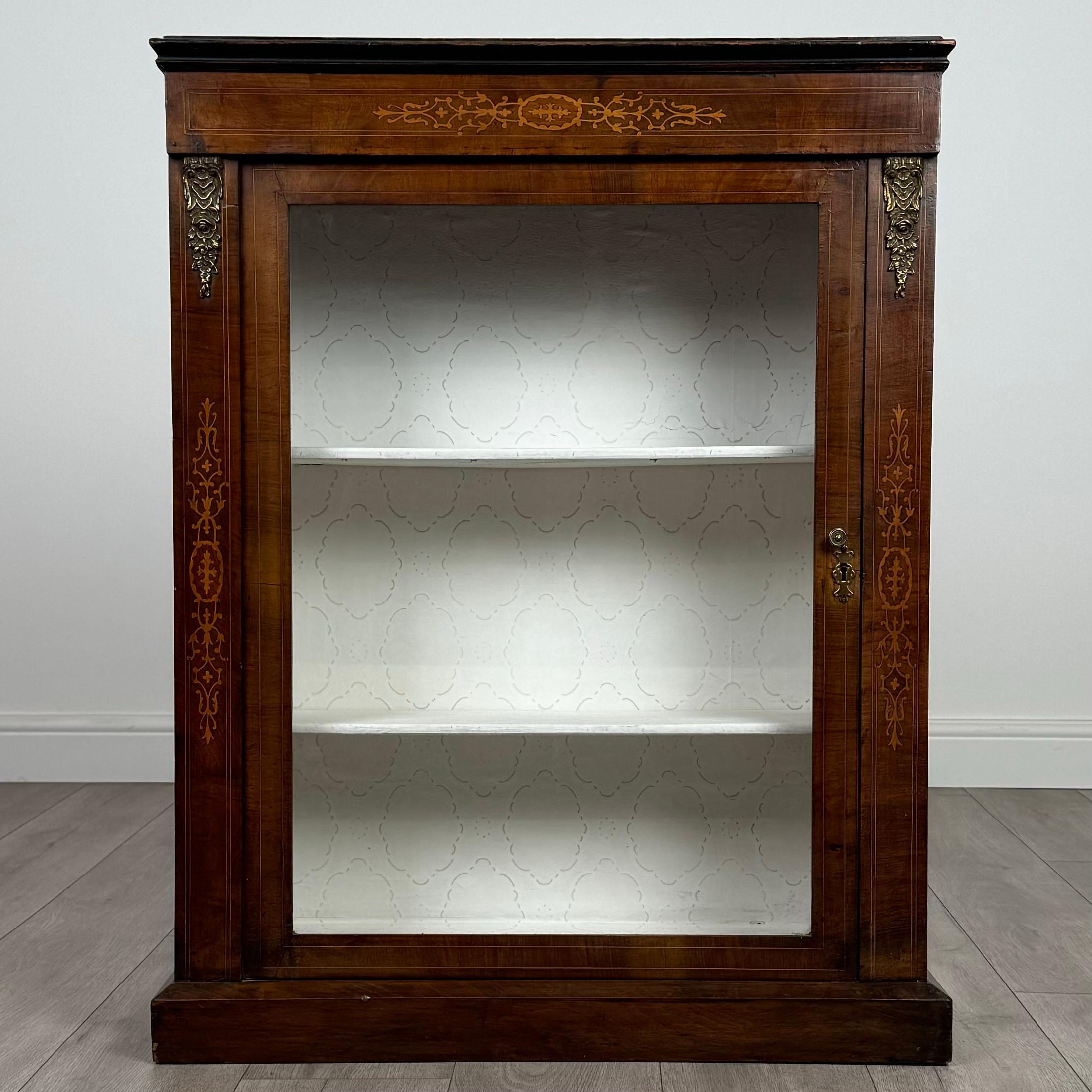Questo squisito mobile da molo del XIX secolo, realizzato in noce pregiato, è un ottimo esempio di artigianato d'epoca. 
Poggiato su una robusta base a plinto, il pezzo è splendidamente intarsiato e impreziosito da splendide decorazioni in ottone