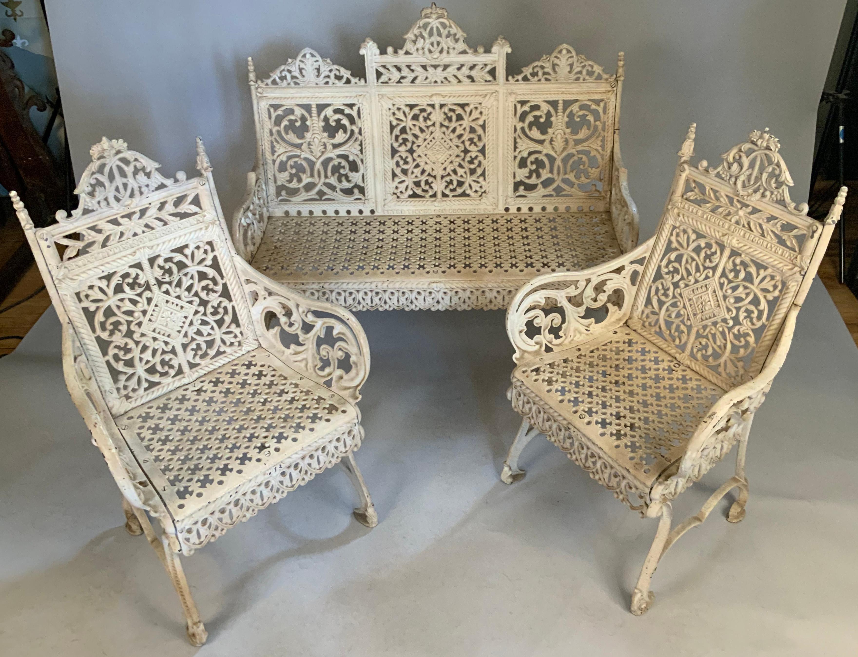 A remarkabe set of cast iron garden furniture by Peter Timmes, Brooklyn. c. late 19th century. 
The set consists of a bench and matching pair of chairs. 

Decorated with Gothic tracery patterns of scrolls and acanthus having a pierced seat.
