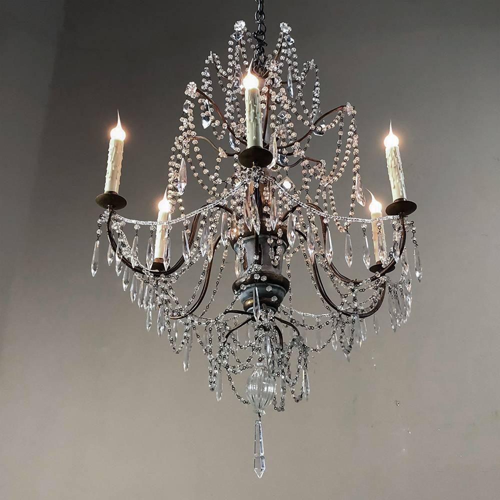 Antique Italian 19th century crystal and silver leaf carved wood chandelier lends a grace that no other type of light fixture can! Sparkling crystals in an intriguing draped design are set off by the fully lighted chandelles with wax candle sleeve