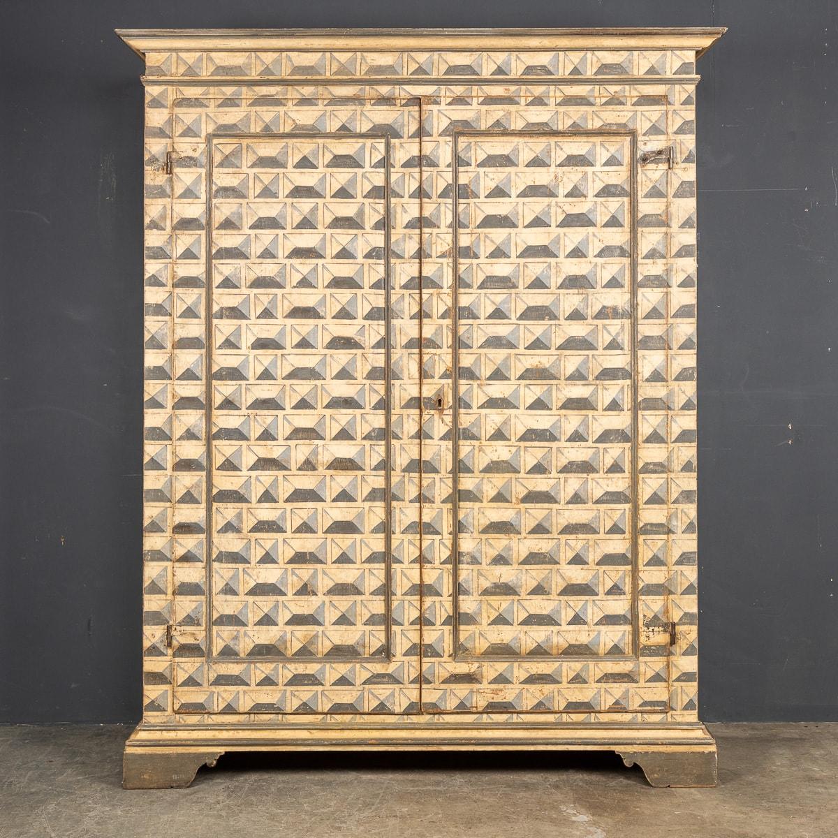 Antique 19th Century Italian wooden armoire, later painted in a striking geometric pattern. The armoire features centre opening cupboard doors revealing an internal hanging rail fitting and a wide drawer at the very bottom. A wonderful and rustic