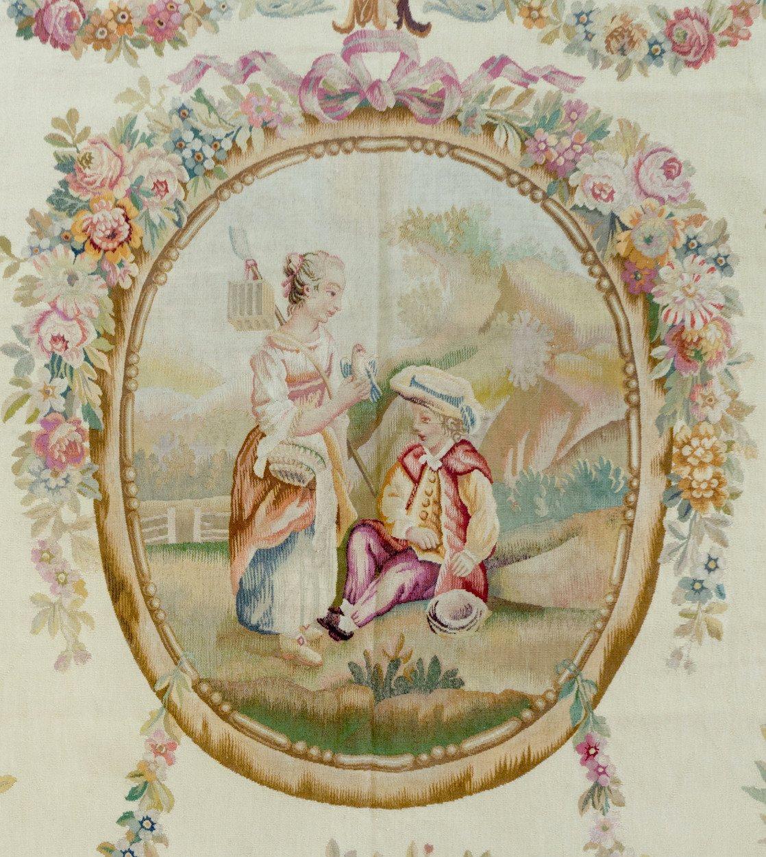 This is a lovely antique 19th century ivory ornate floral French Aubusson tapestry. It has floral garlands and an oval window looking onto a scene with a woman presenting a dove to a seated boy. It measures: 5.3 x 6.6 ft.

If you are interested in