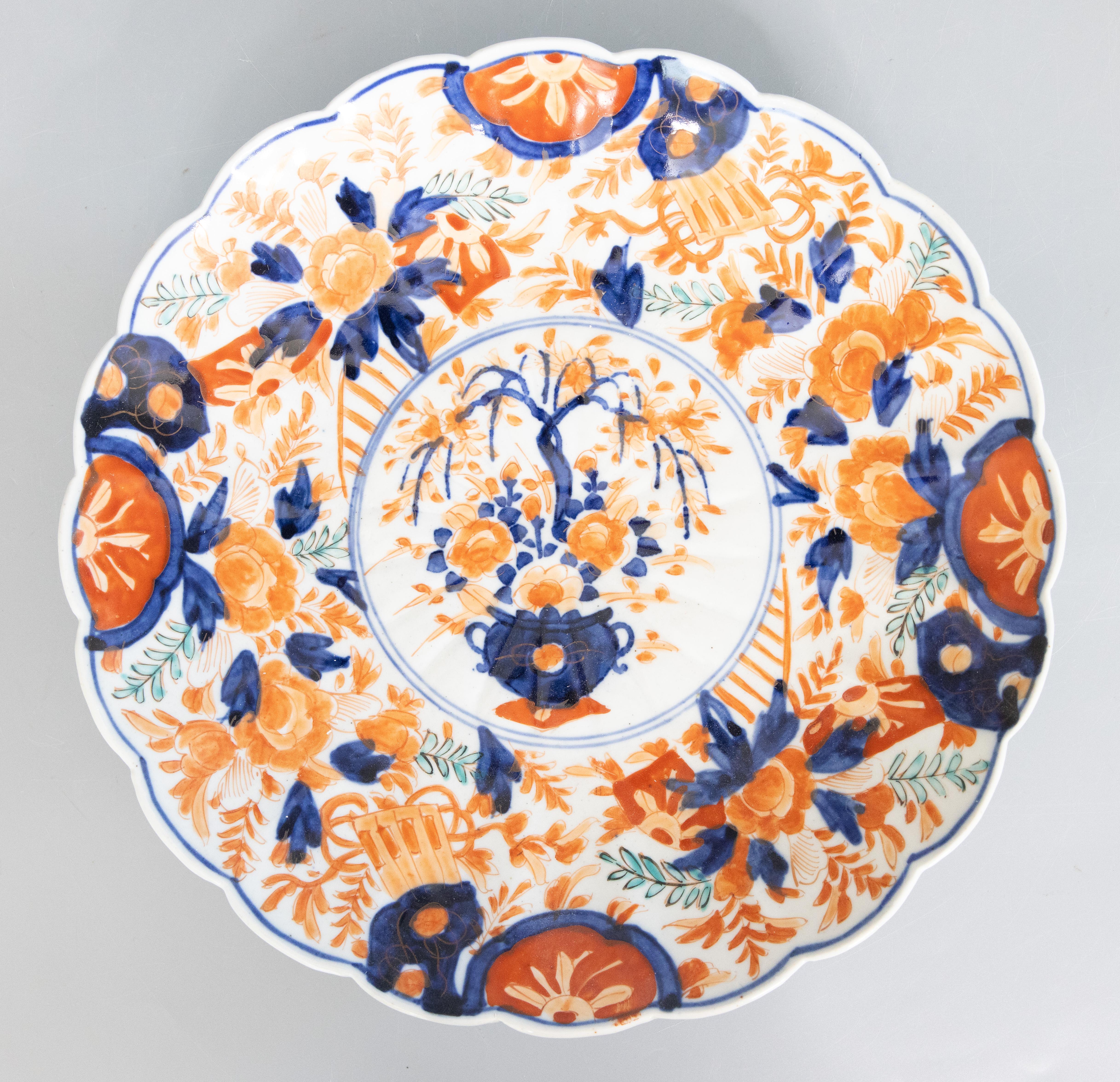 A gorgeous pair of 19th-Century Japanese Meiji Period Imari porcelain chargers with hand painted floral decorations in the traditional Imari colors. These fine large plates have lovely scalloped edges, lobed design, and the center is painted with a