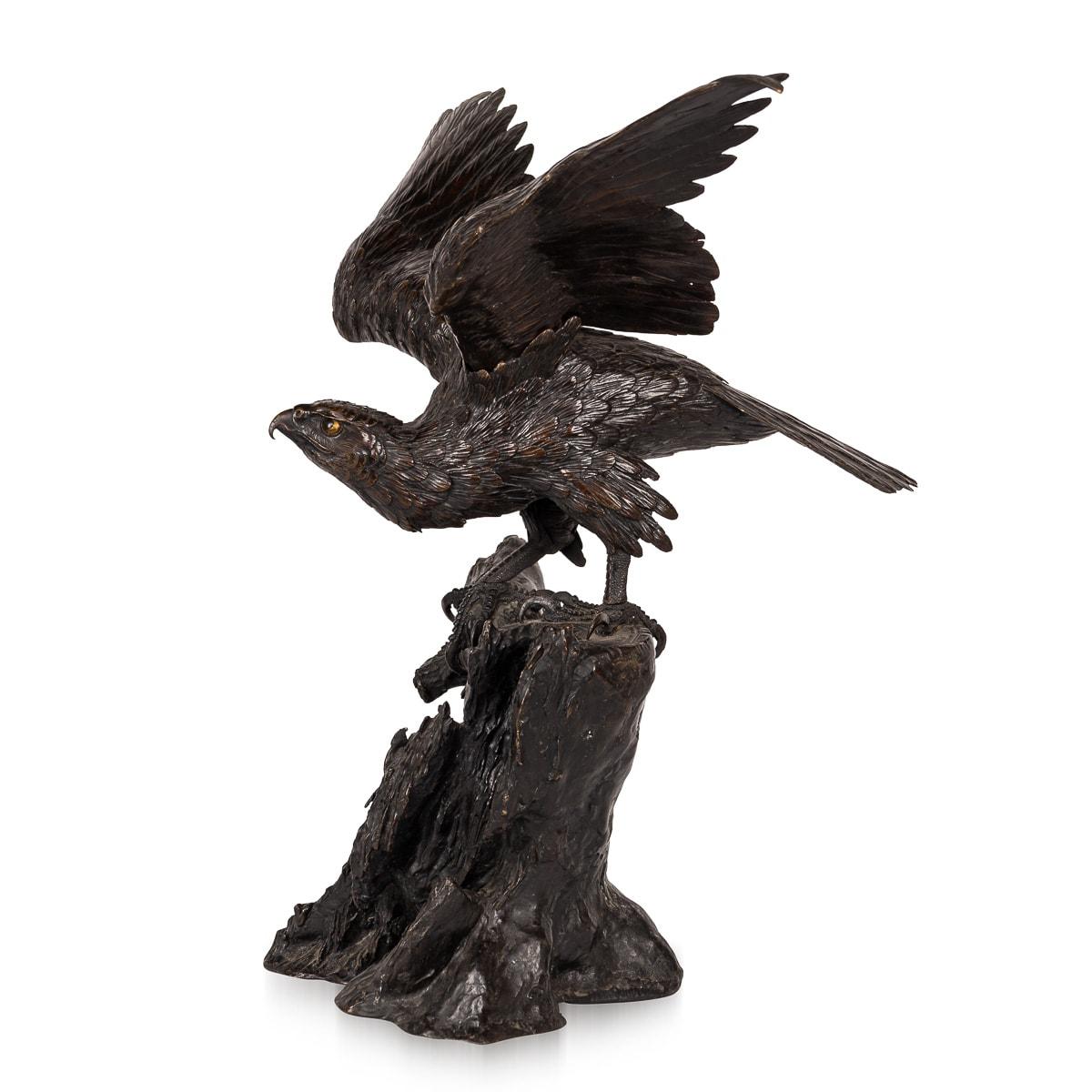 Antique late 19th Century Japanese, grand bronze sculpture of an eagle from the Meiji period, poised atop rocky formations, with its wings gracefully extended. The majestic bird appears vigilant, poised to swoop down and seize its prey. Its head