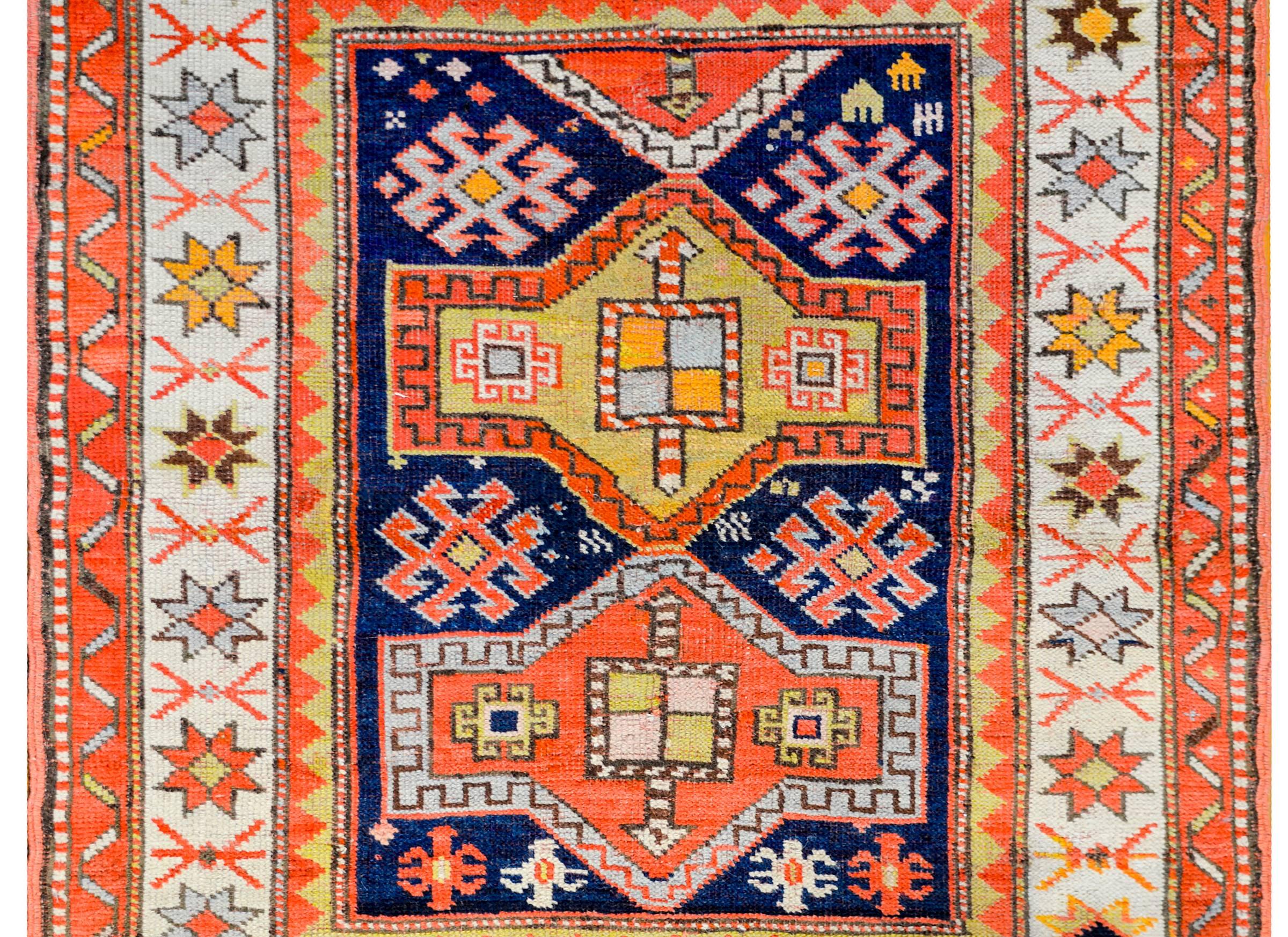 Ancien tapis kazakh Perisan du XIXe siècle présentant un magnifique motif tribal avec des fleurs stylisées et d'autres formes géométriques, tissé en laine de couleur cramoisie, indigo clair et foncé, or et vert sur un fond indigo foncé. La bordure