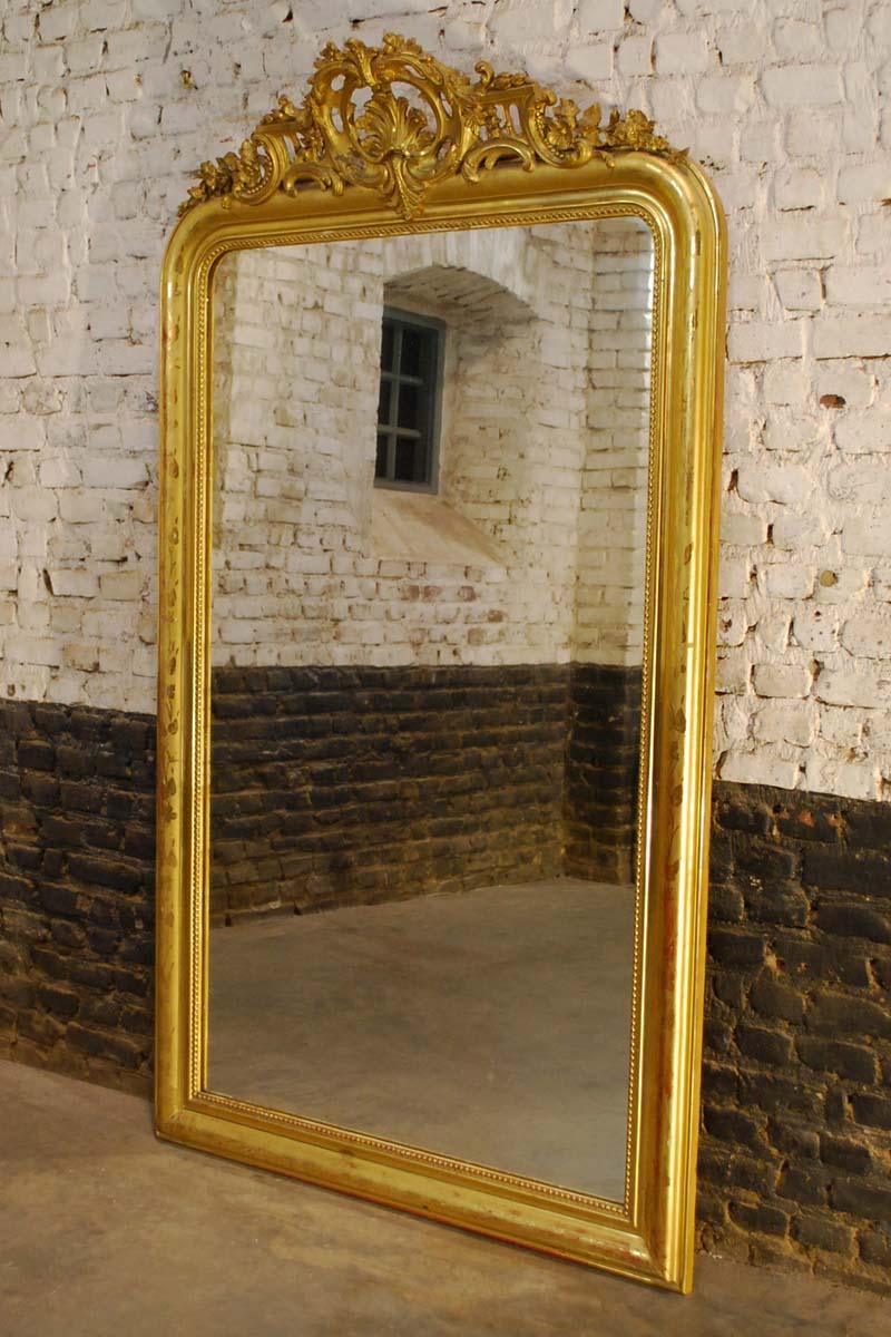 This beautiful antique gold gilded wall mirror is made in southern France around 1850. 
It is made in the then fashionable Louis Philippe style with its rounded upper corners and symmetrical crown on top. This mirror is in very good authentic