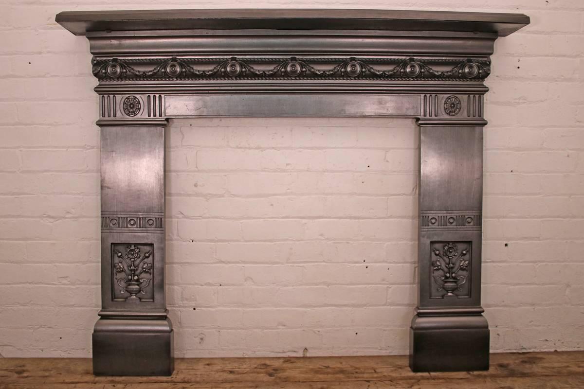 Reclaimed late Victorian cast iron fireplace surround with a chain of swags of laurel and discs to the frieze above jambs decorated with inset panels finely cast with aesthetic flowers and urn, circa 1880. 

Finished with traditional black grate