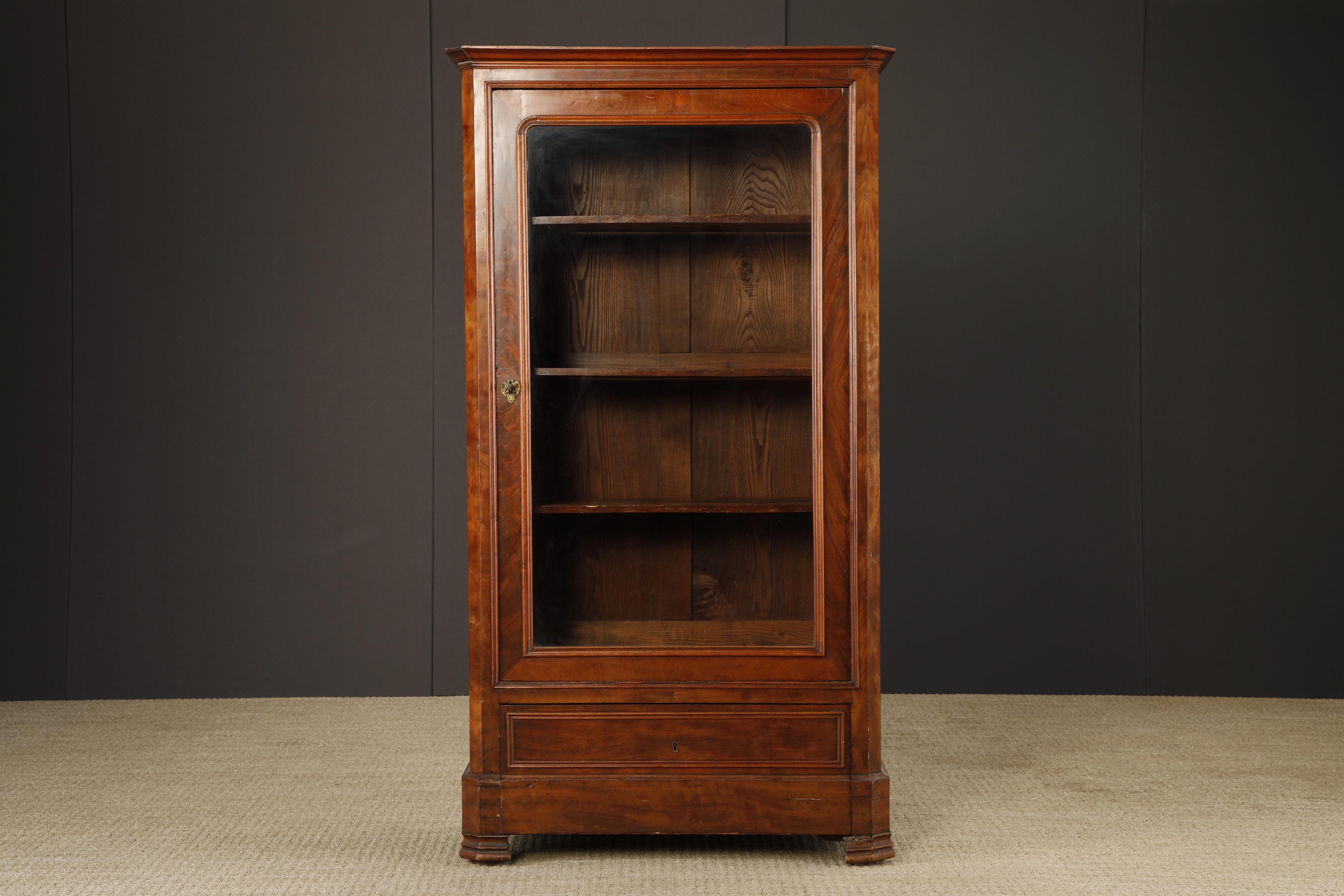This antique display cabinet is either from the Louis Philippe period or adjacent, we are listing it as in the style of however it has the age and appearance to be of the period. Possibly made from Mahogany, this cabinet showcases items behind the