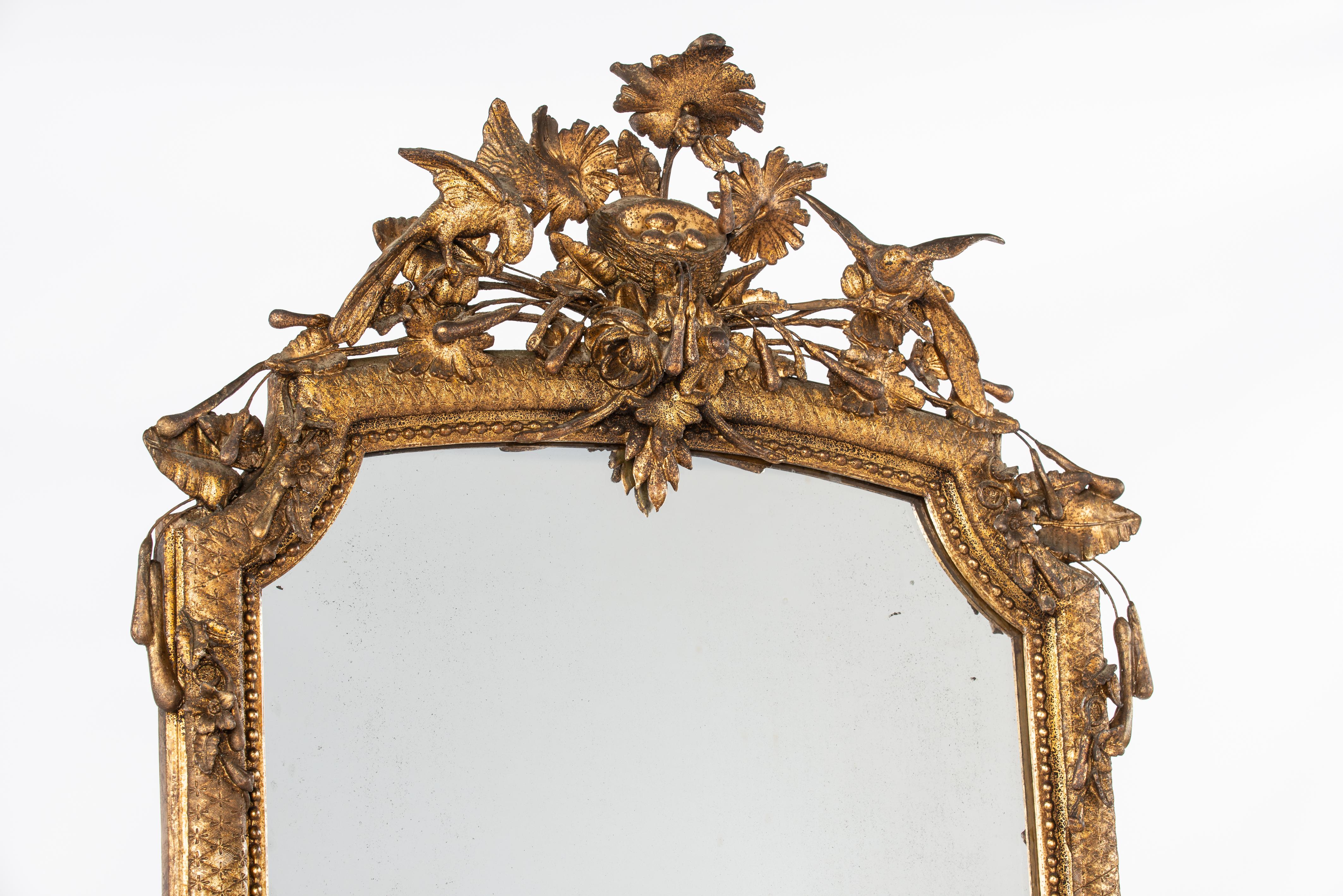 On offer here is a stunning and rare tall pier mirror that was made in Southern France in the mid-19th century, circa 1850. The mirror frame is lavishly adorned with many natural ornaments such as flowers, leaves, and reed plumes. At the top of the