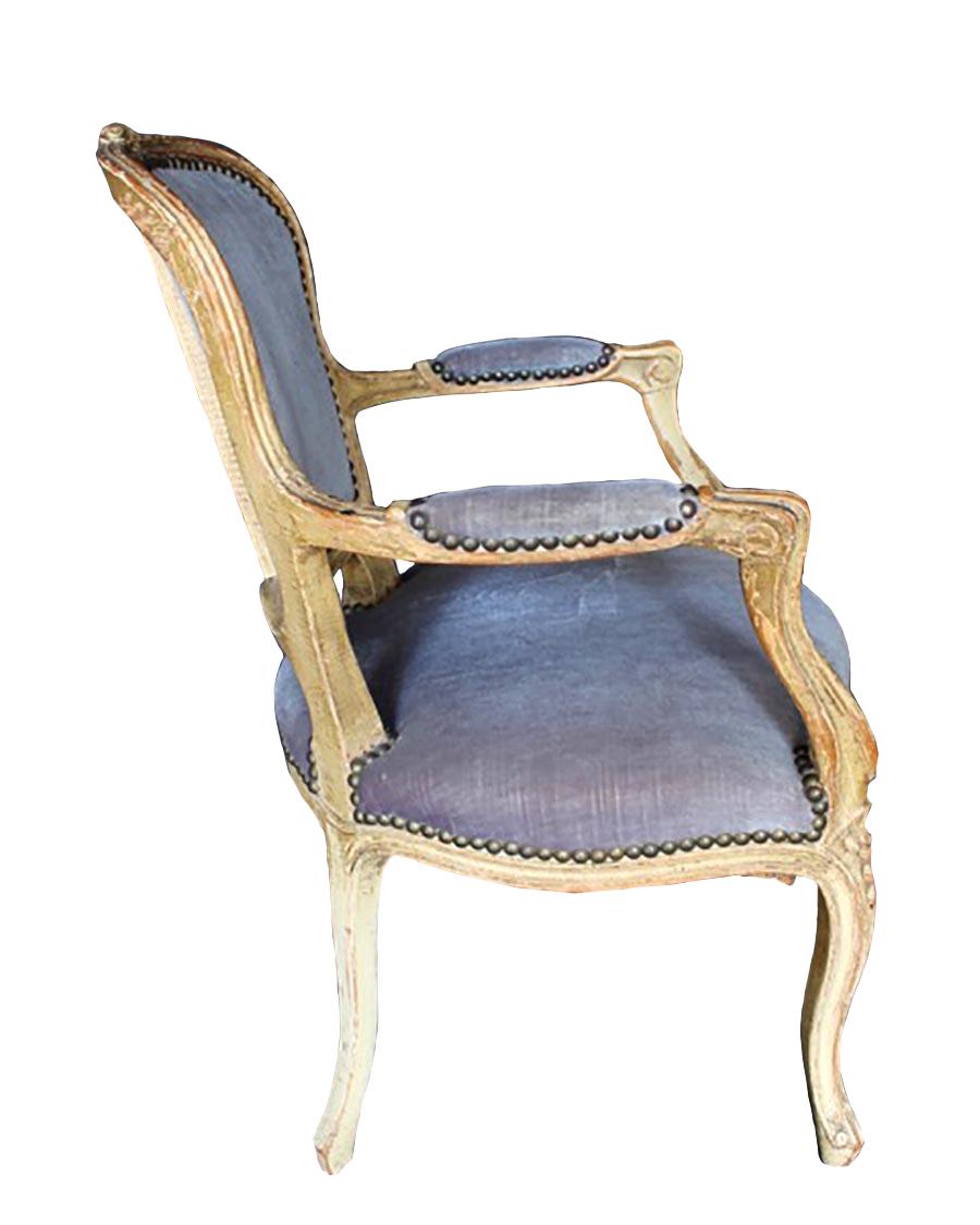 This 19th century Louis XVI wooden child's chair is made of carved wood and upholstery, with a good patina. The elegantly carved frame is finished in a royal gold color with blue or purple upholstery lined with decorative studs. The seat height is