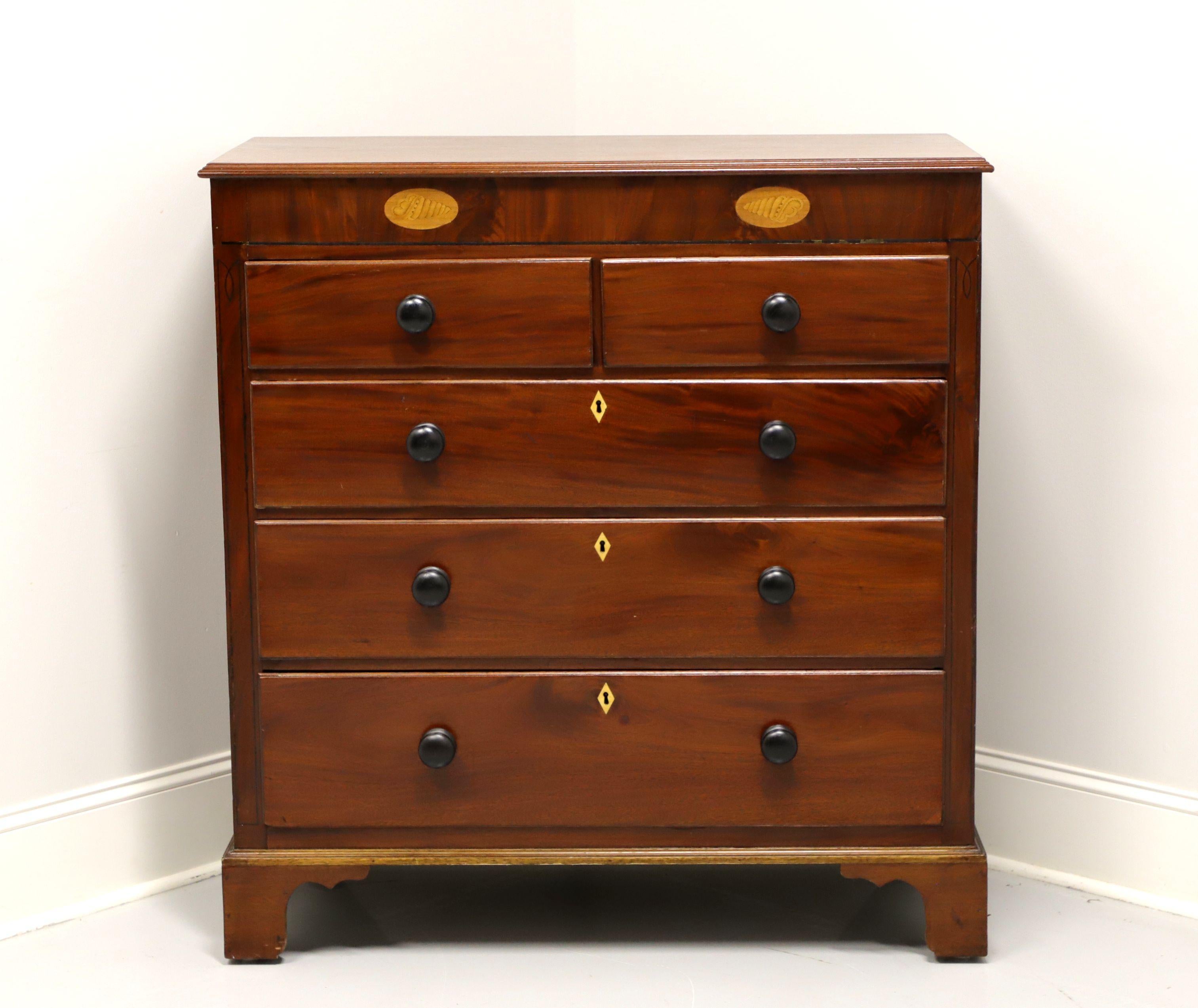 An antique American chest of drawers in the Chippendale style, unbranded. Mahogany, inlaid satinwood, inlaid escutcheons, wood knobs and bracket feet. Features two smaller over three larger dovetail drawers with locks. Made in the USA, in the 19th