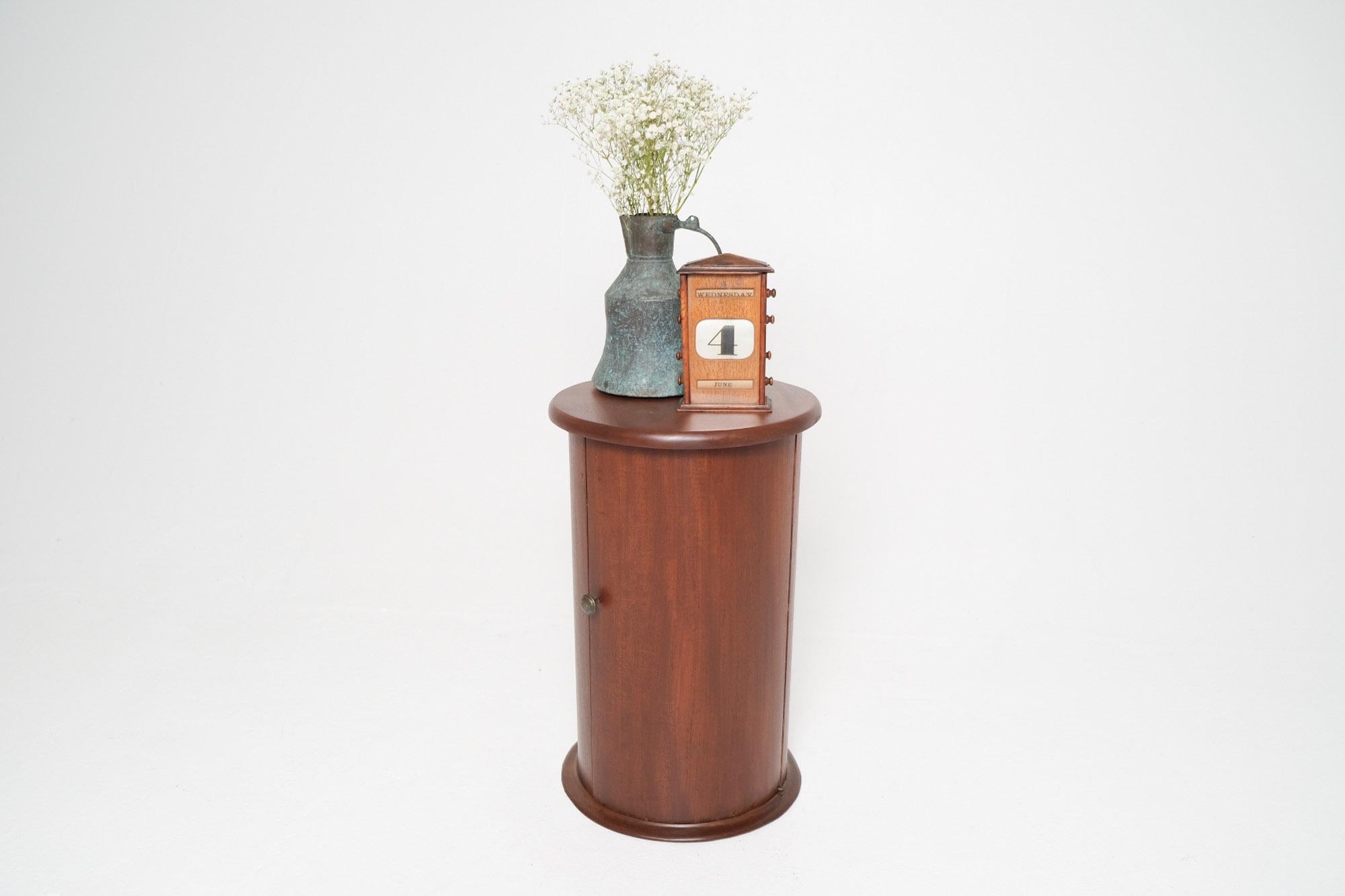 A rare and elegant Victorian cylindrical cabinet crafted in solid mahogany, dating to the late 19th century. This distinctive piece features a rounded body with molded top and base, a flush-mounted door with brass knob, and a single interior shelf