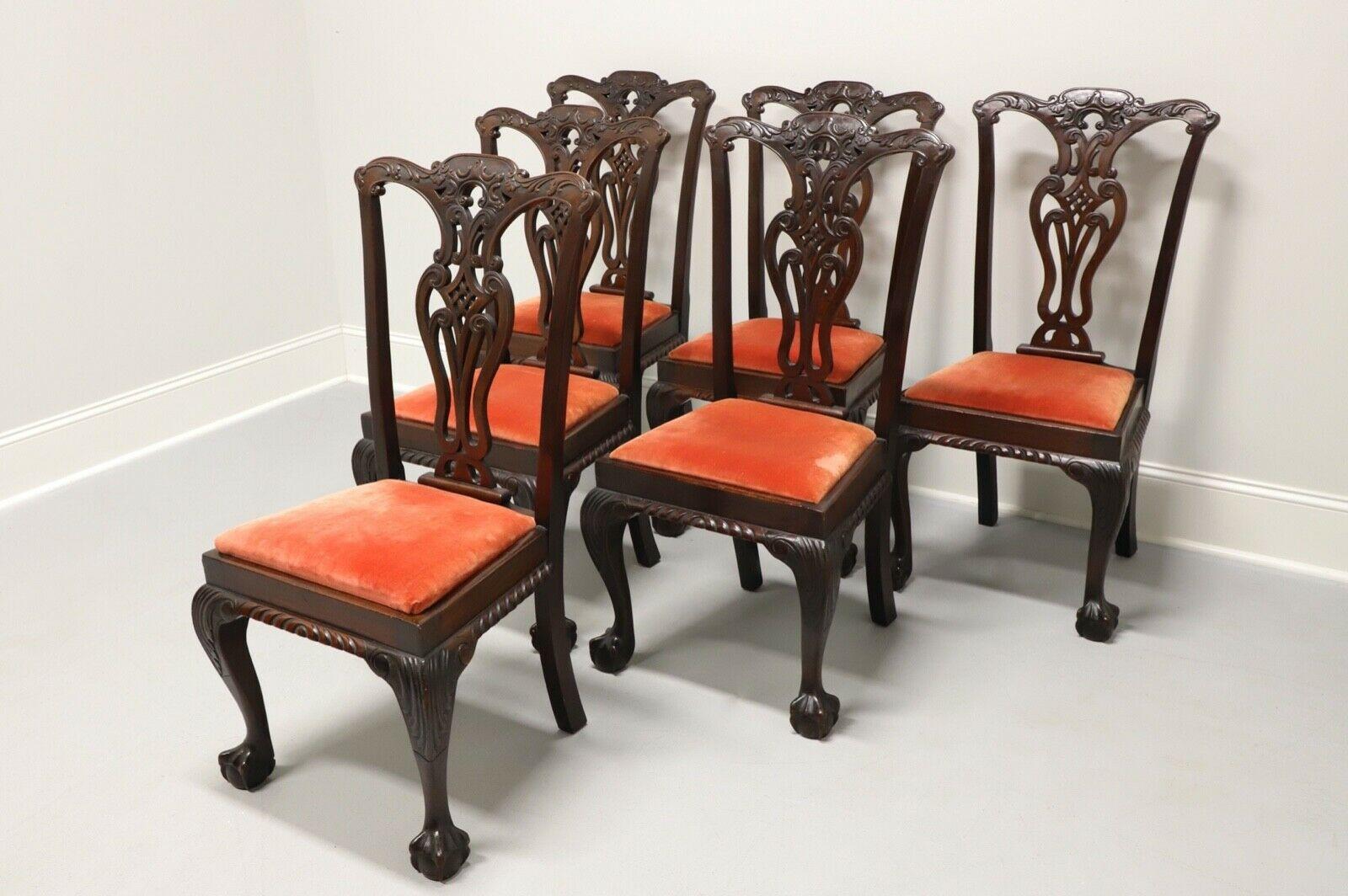 A set of six antique dining side chairs in solid Mahogany, unbranded. English Chippendale style with carved backsplats, red crushed velvet upholstered seats, gadroon carved aprons, cabriole legs with carved knees and ball in claw feet. Made in